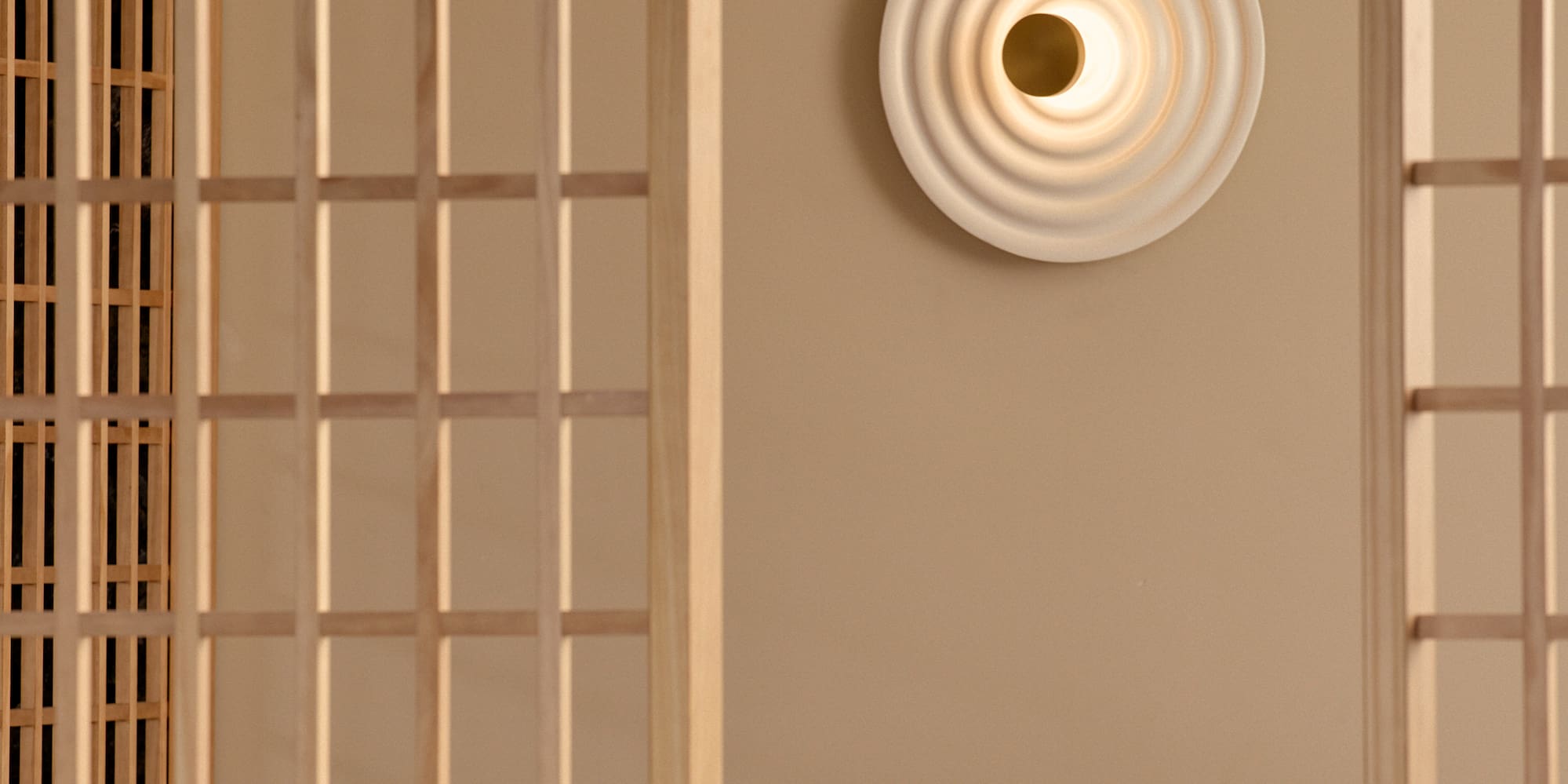 a room with a bed and a wall with a light on the wall