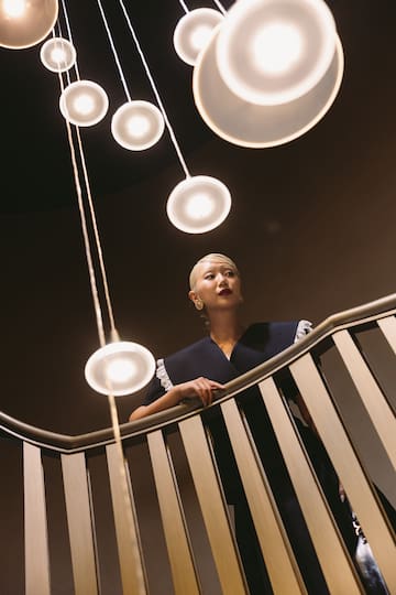 a woman standing on a staircase with lights from the ceiling