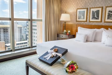 a bed with a gift and flowers in a room with a window