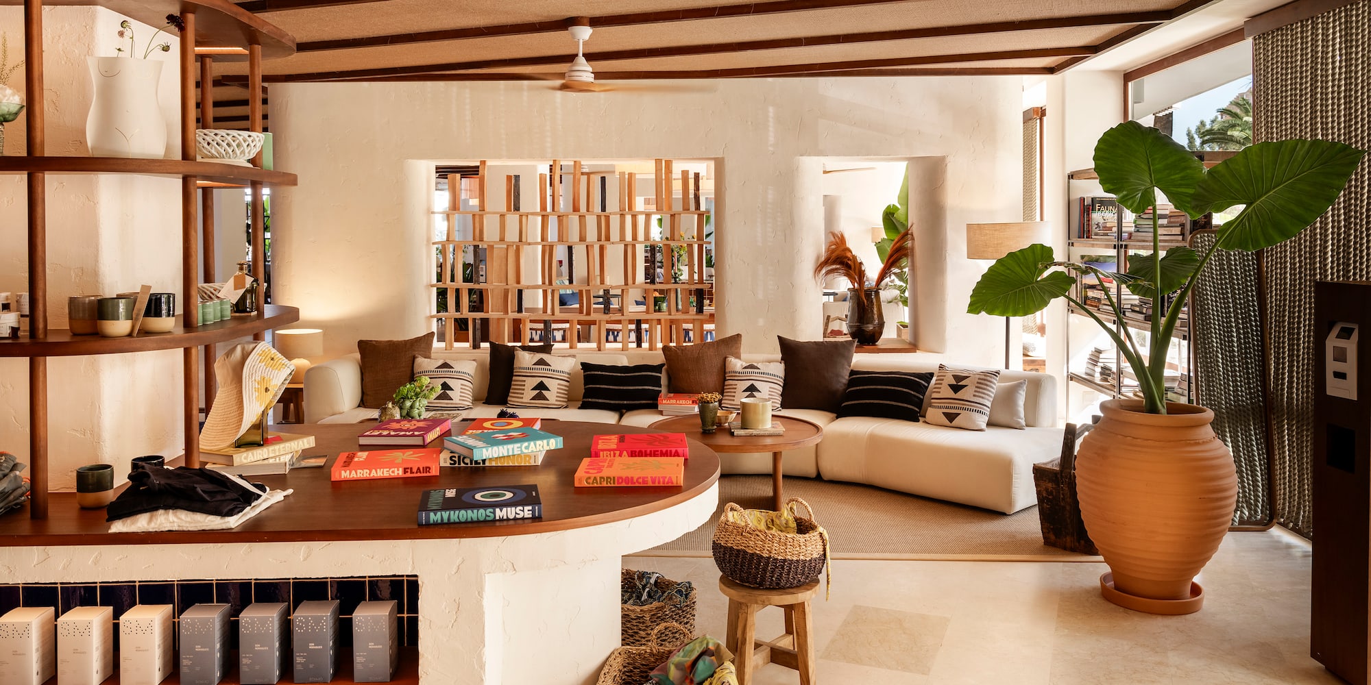 Modern resort lounge with white sofa, colorful books, potted plant, and natural decor.