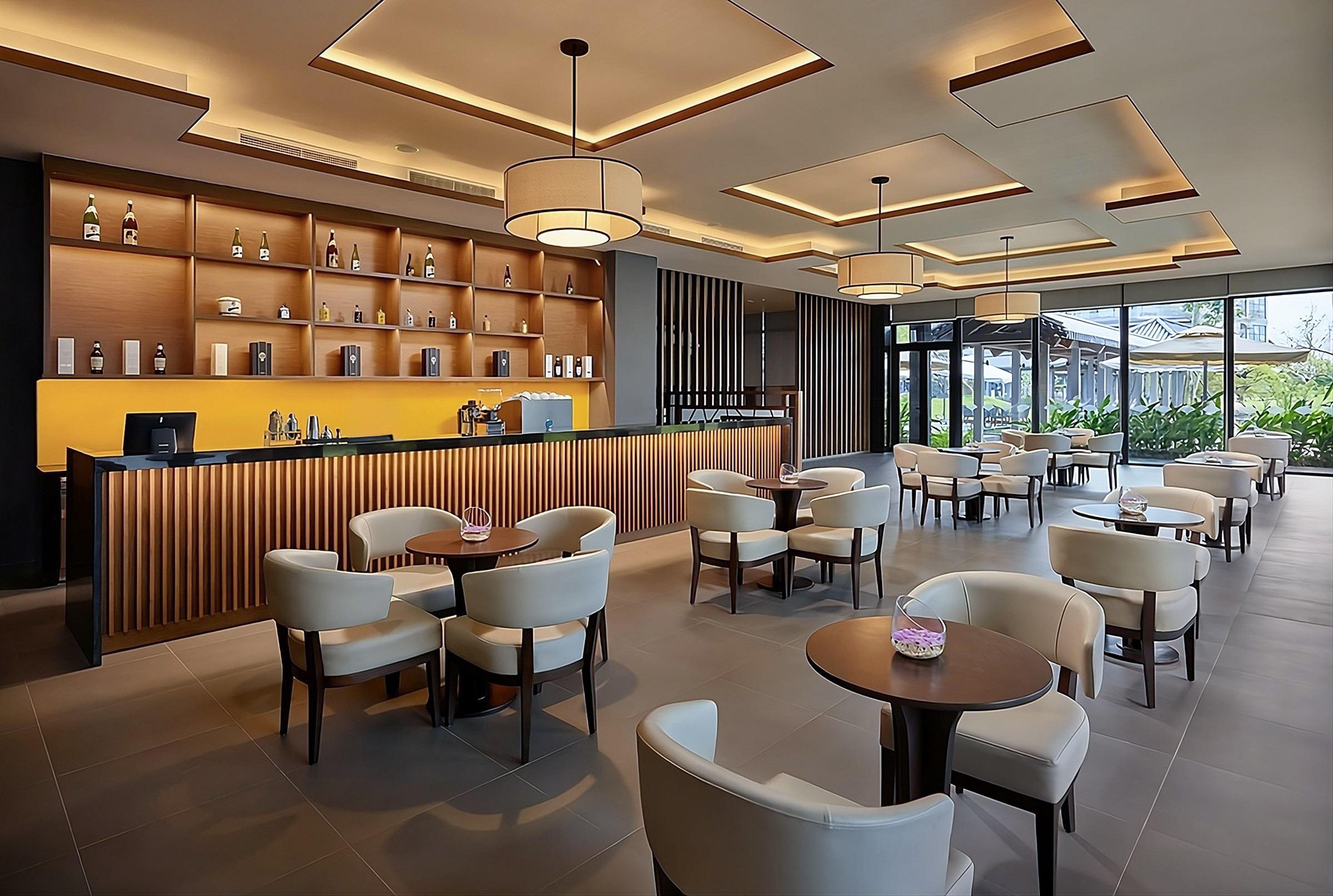 Modern bar lounge with wooden counter, elegant seating, and outdoor views.
