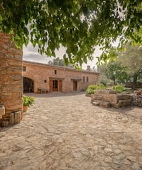 a stone courtyard with a stone building and a tree