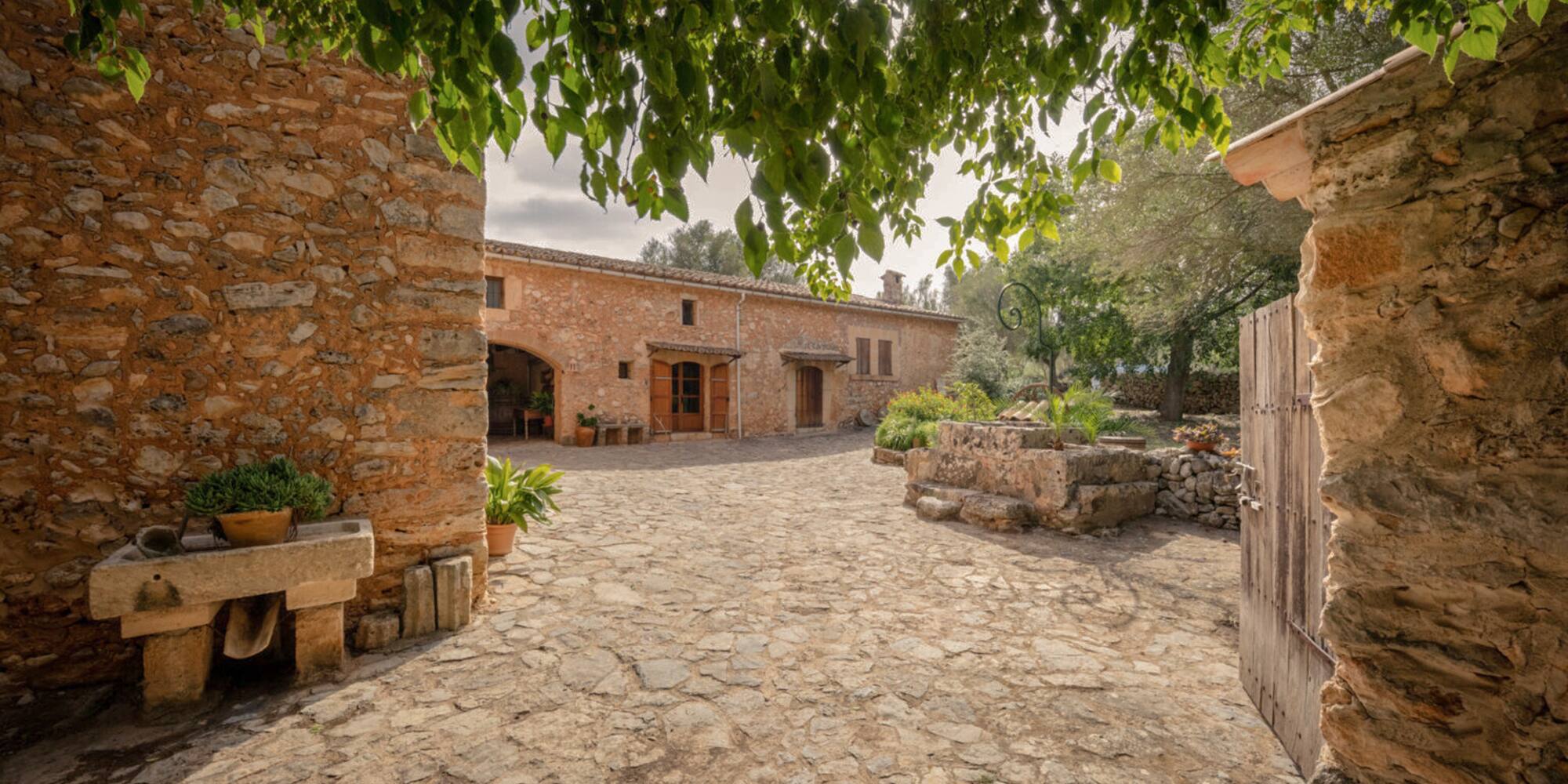 a stone courtyard with a stone building and a tree