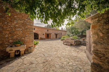 a stone courtyard with a stone building and a tree