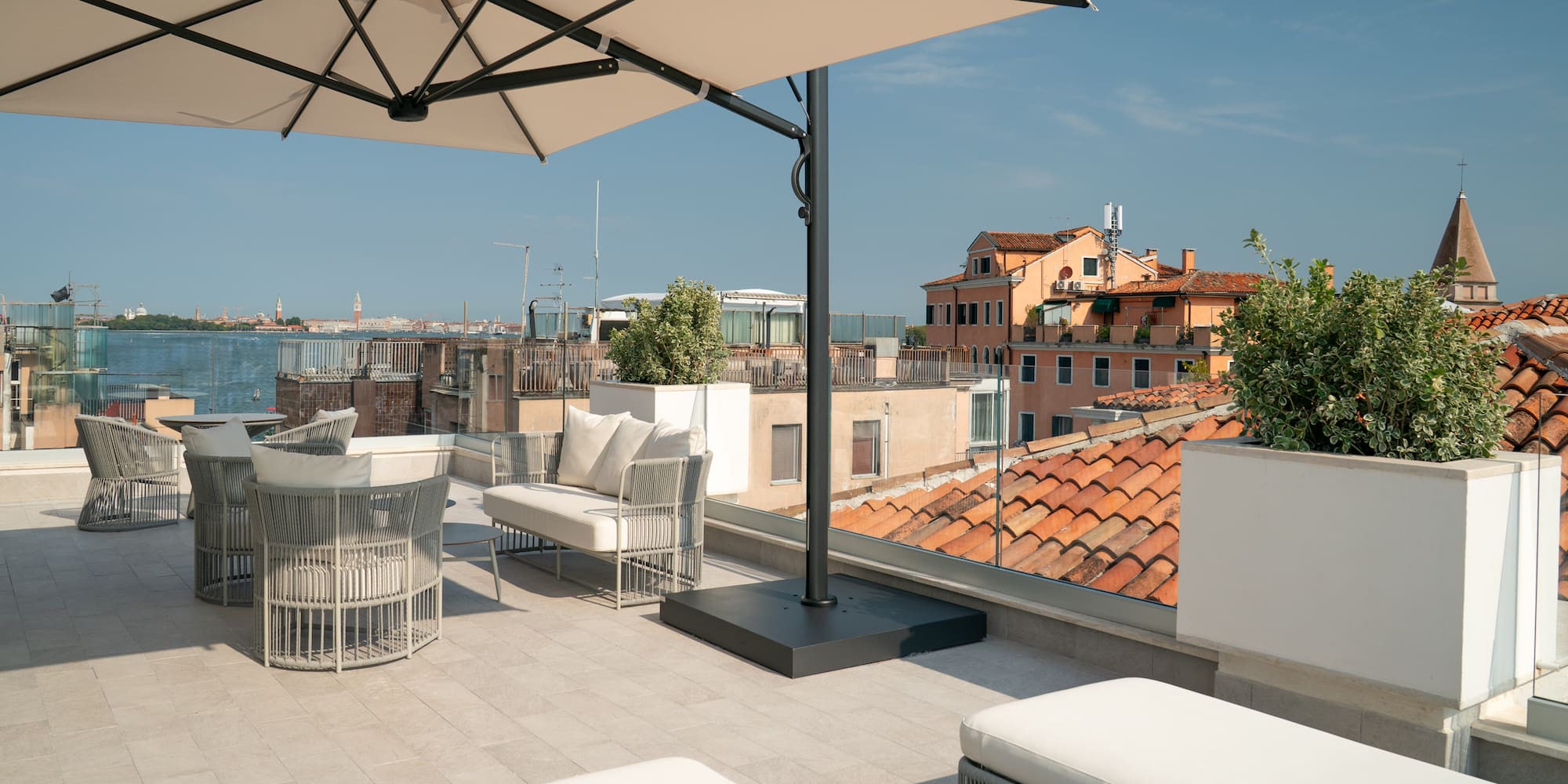 Modern outdoor patio with beige umbrella and panoramic Venice skyline.