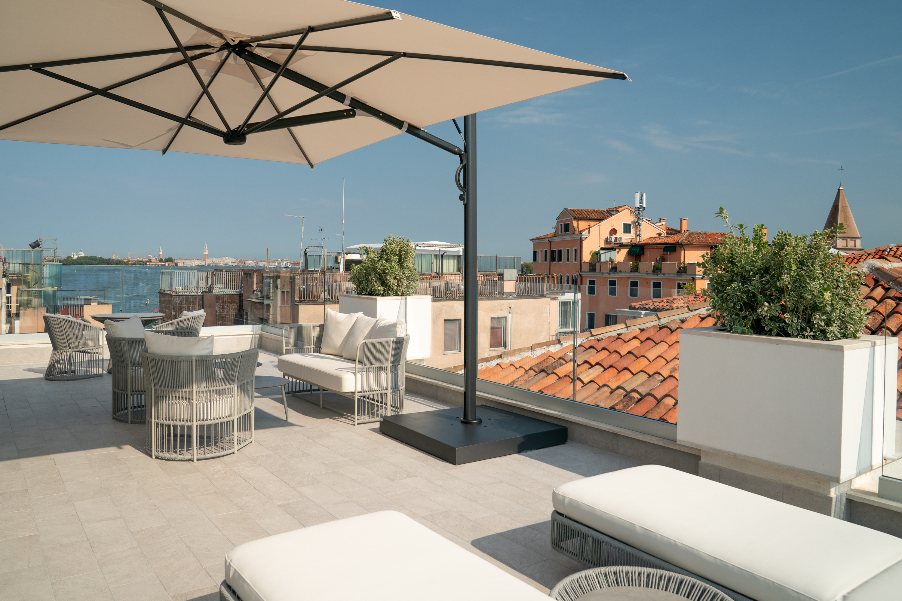 Modern outdoor patio with beige umbrella and panoramic Venice skyline.
