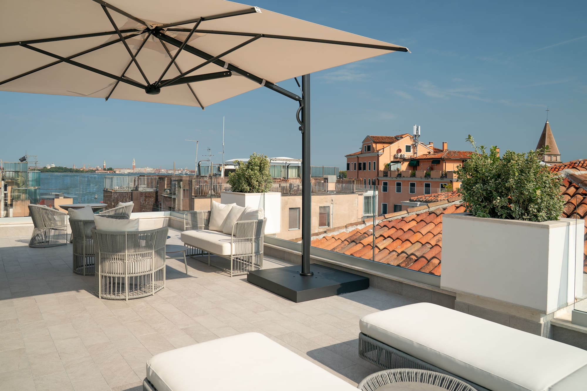 Modern outdoor patio with beige umbrella and panoramic Venice skyline.