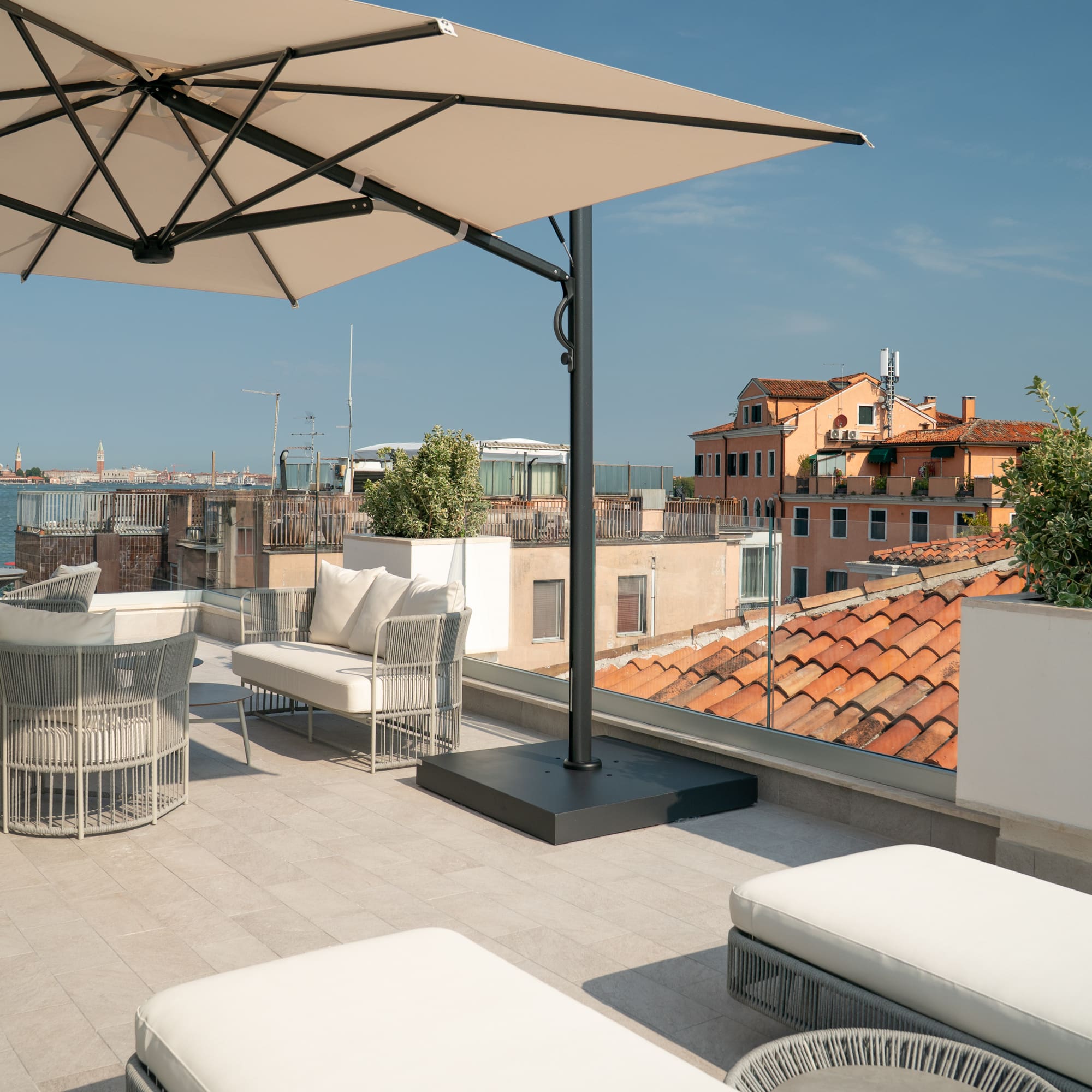 Modern outdoor patio with beige umbrella and panoramic Venice skyline.
