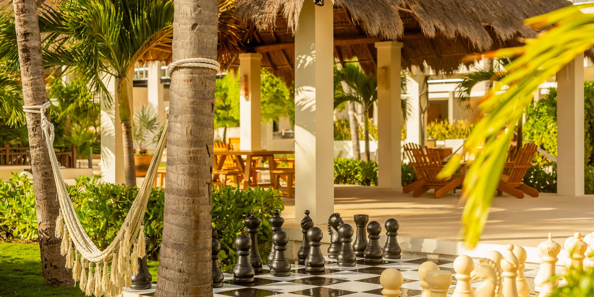 Tropical resort featuring outdoor giant chess, hammock, and thatched gazebo.