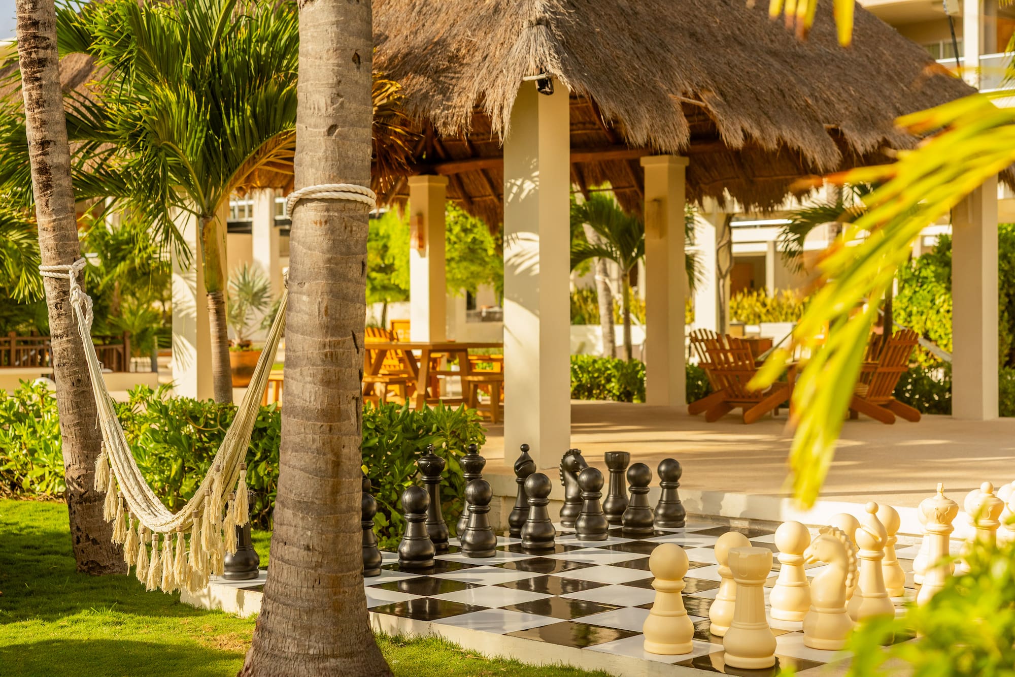 Tropical resort featuring outdoor giant chess, hammock, and thatched gazebo.