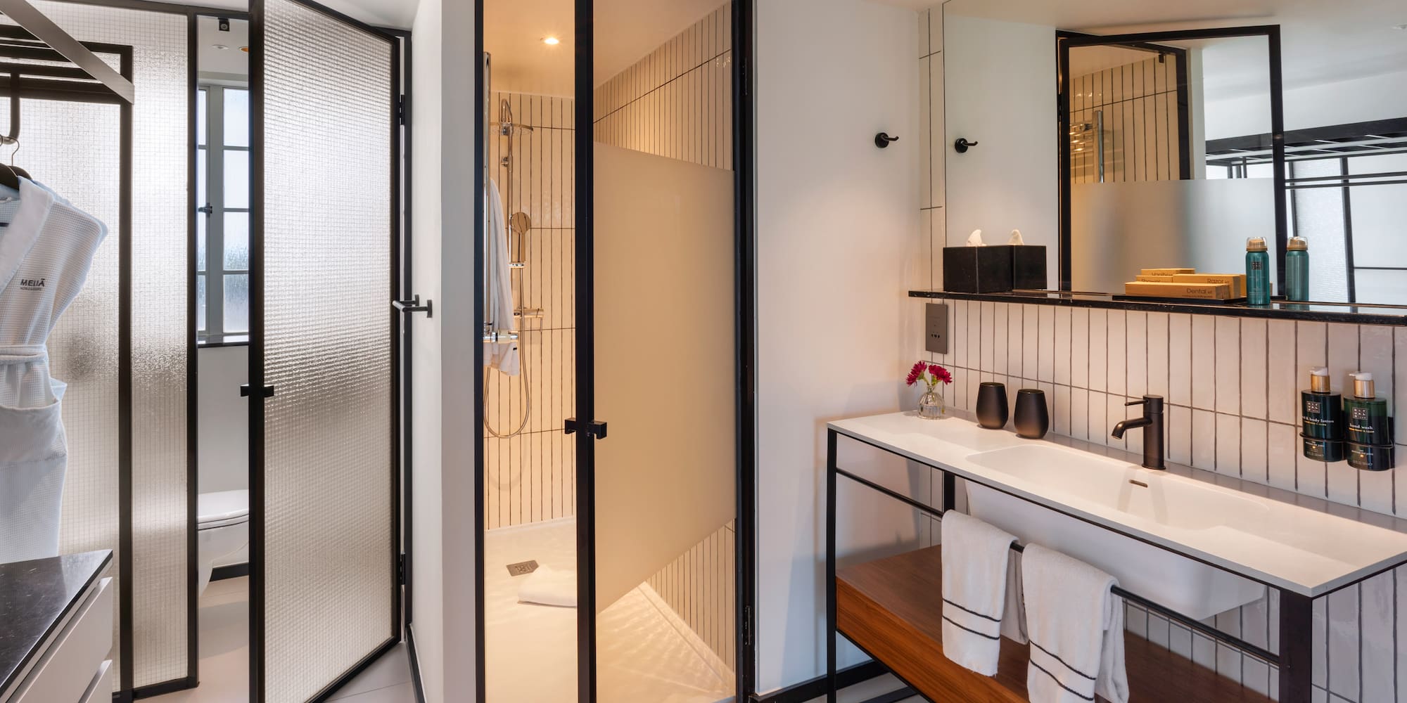 Sleek hotel bathroom with glass shower, floating vanity, and black accents.