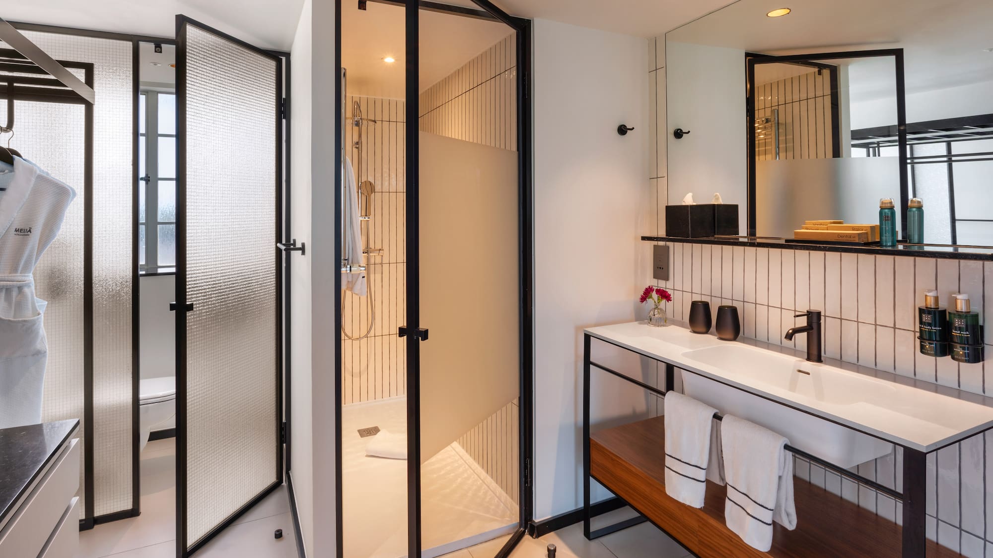 Sleek hotel bathroom with glass shower, floating vanity, and black accents.
