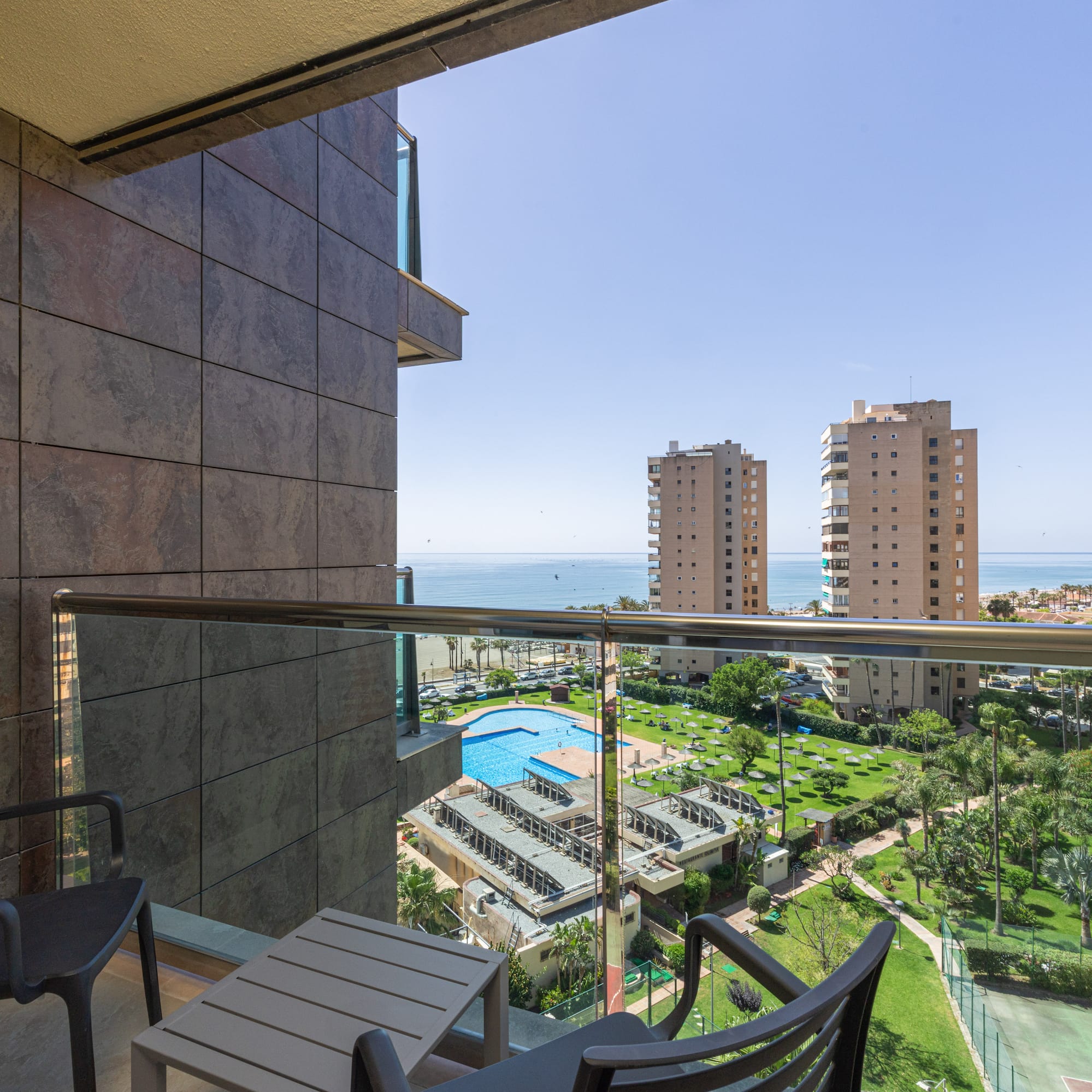Balcony ocean view with swimming pool, resort complex, and city buildings.