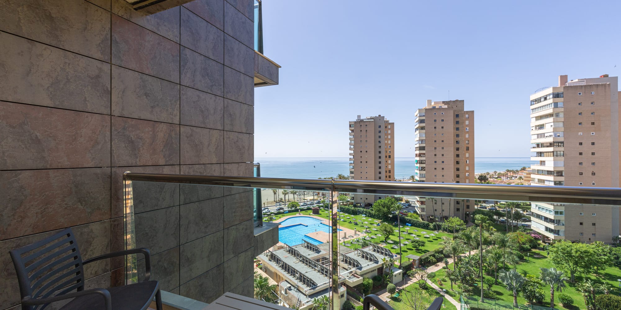 Balcony ocean view with swimming pool, resort complex, and city buildings.