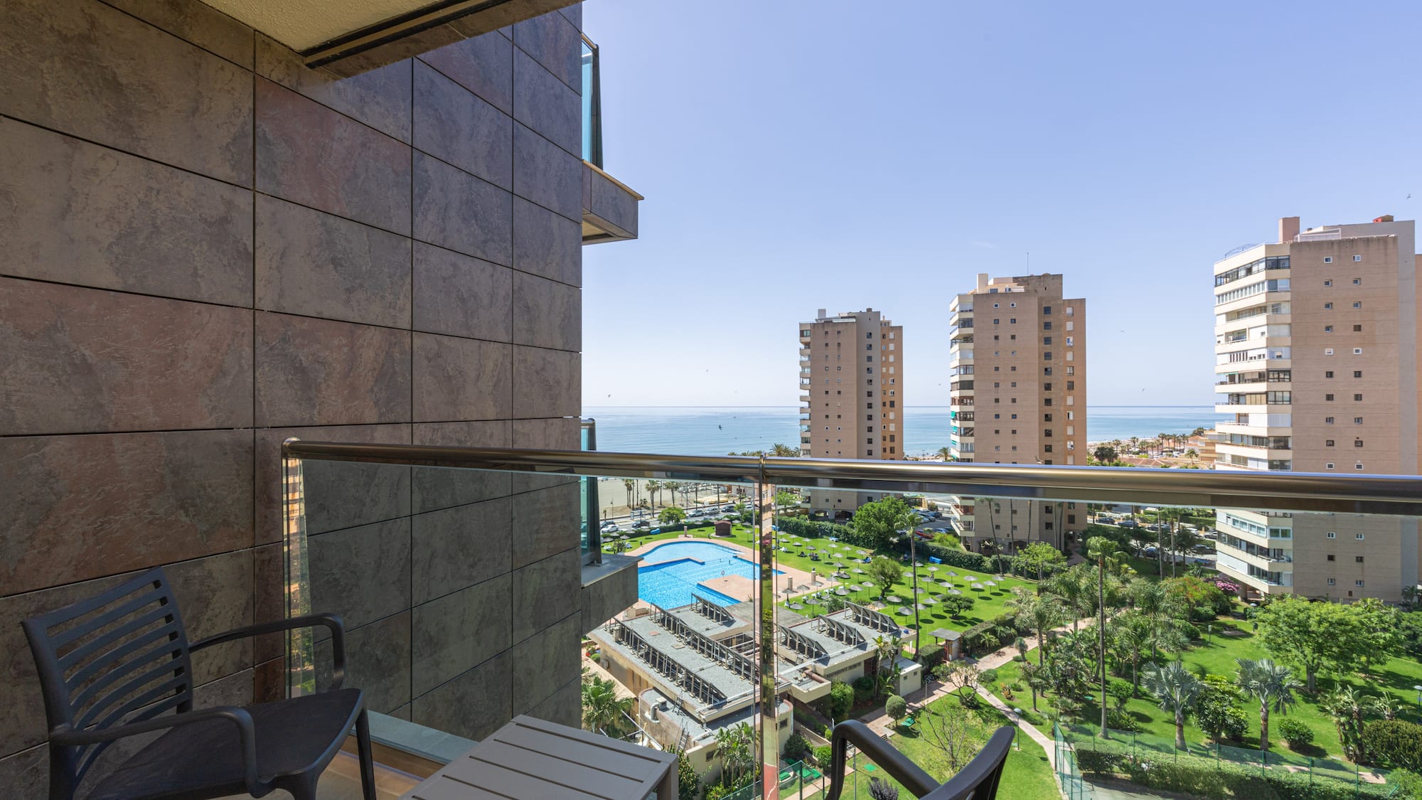 Balcony ocean view with swimming pool, resort complex, and city buildings.