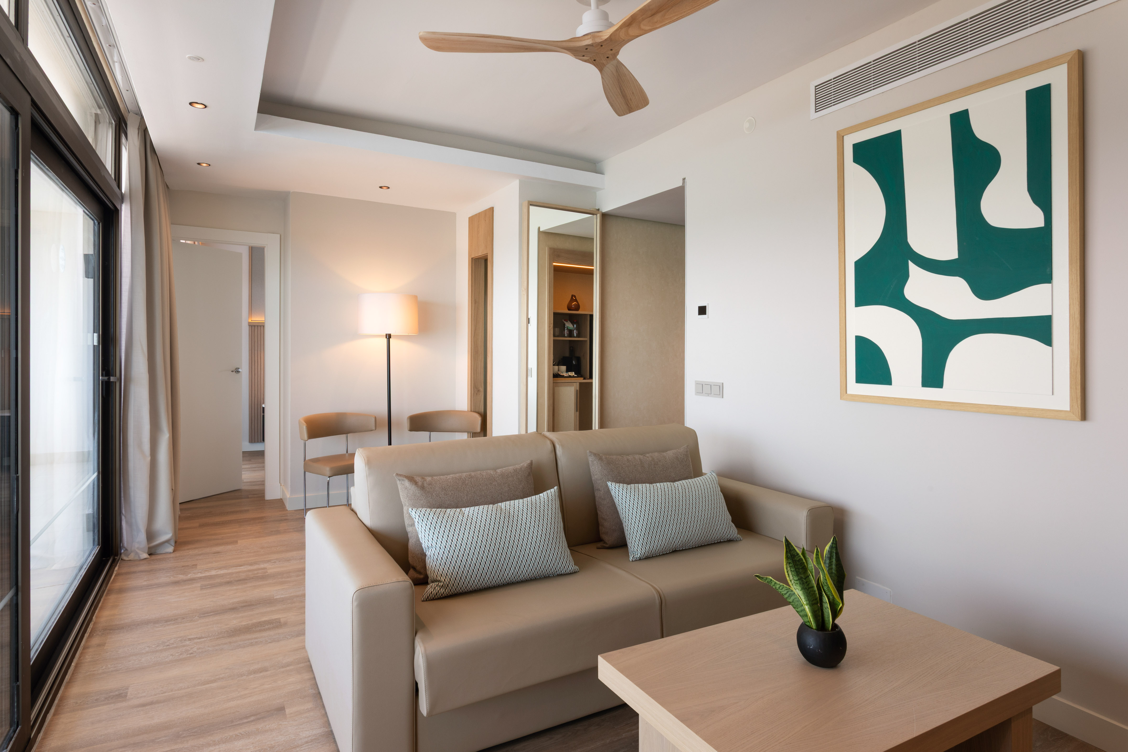 Contemporary living room with sofa, wood floor, abstract art, and ceiling fan.