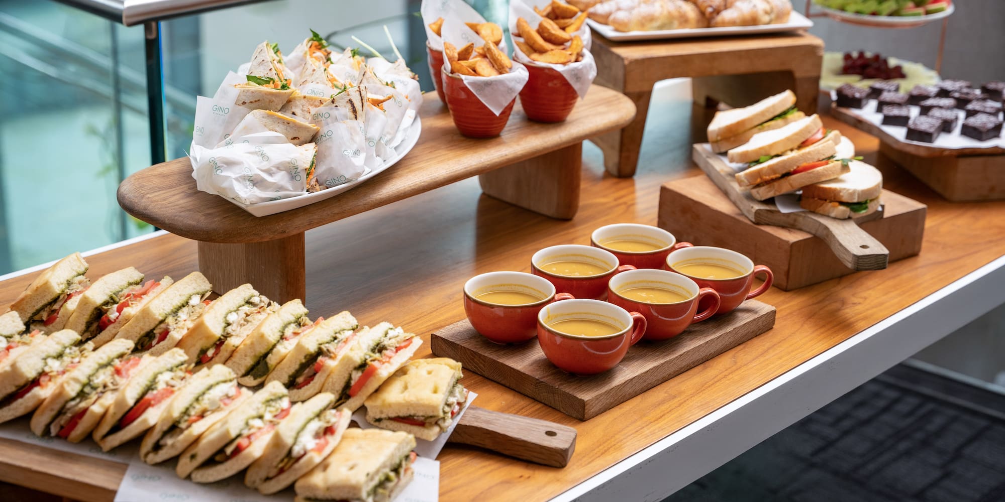 Event lunch buffet: sandwiches, wraps, soup, fries, croissants, and desserts.