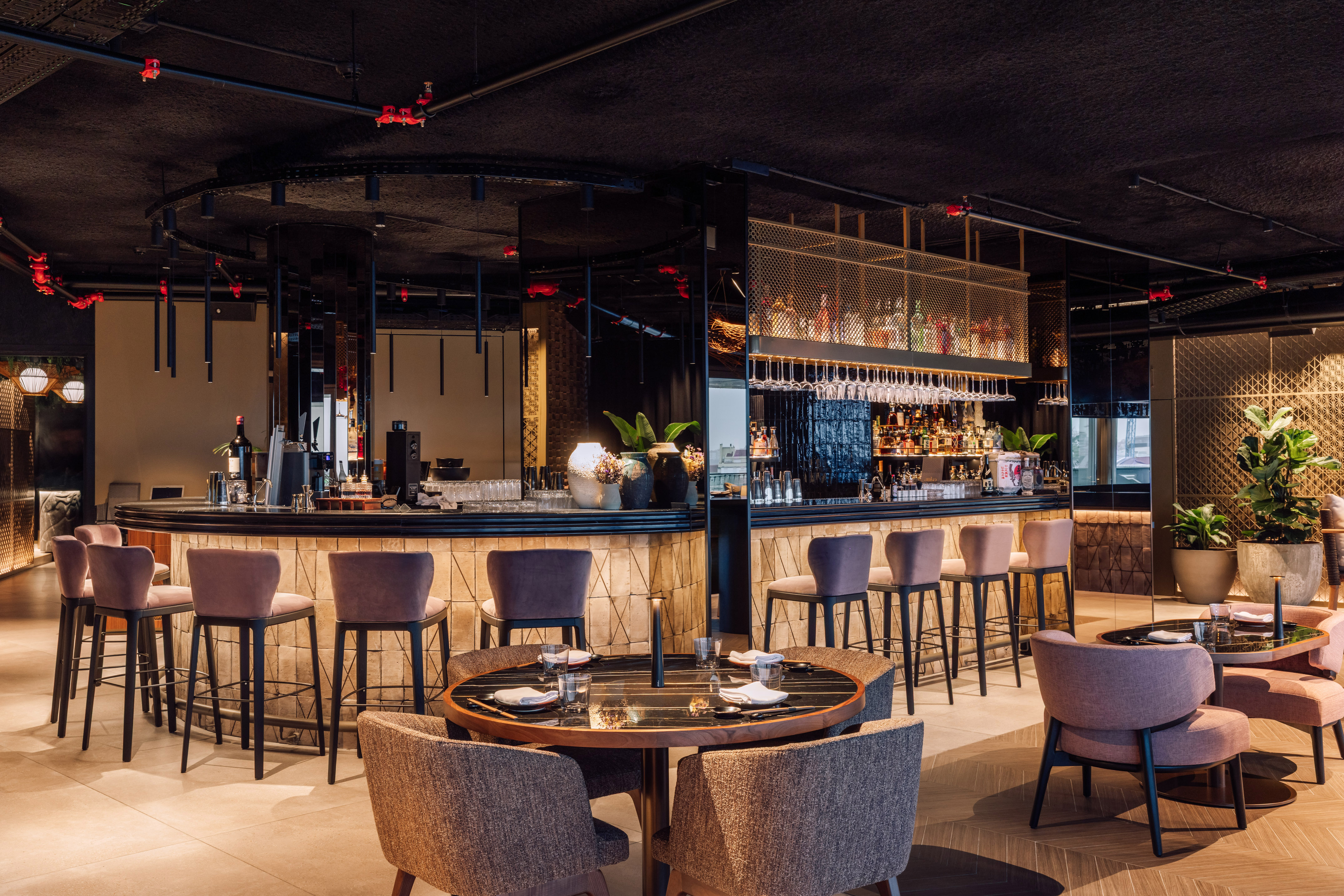 Modern restaurant bar with sleek design, pink bar stools, and elegant dining tables.