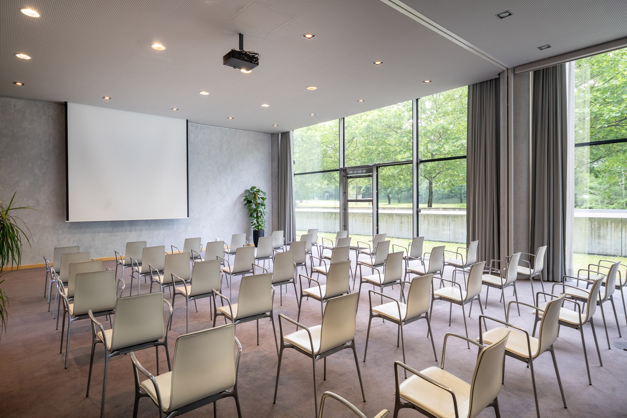 Modern event space with projector screen, chairs, and large windows.
