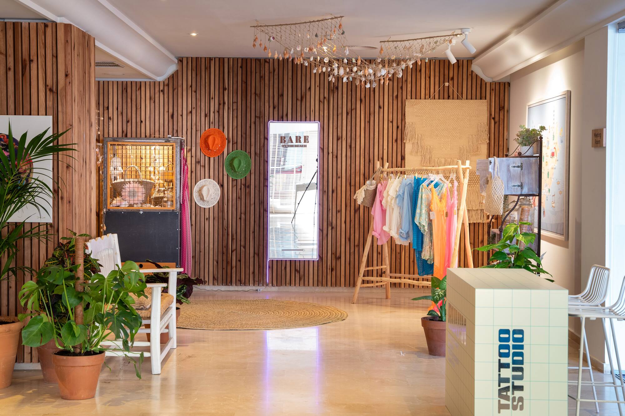 Vibrant clothing boutique with wooden walls, plants, and a Tattoo Studio.