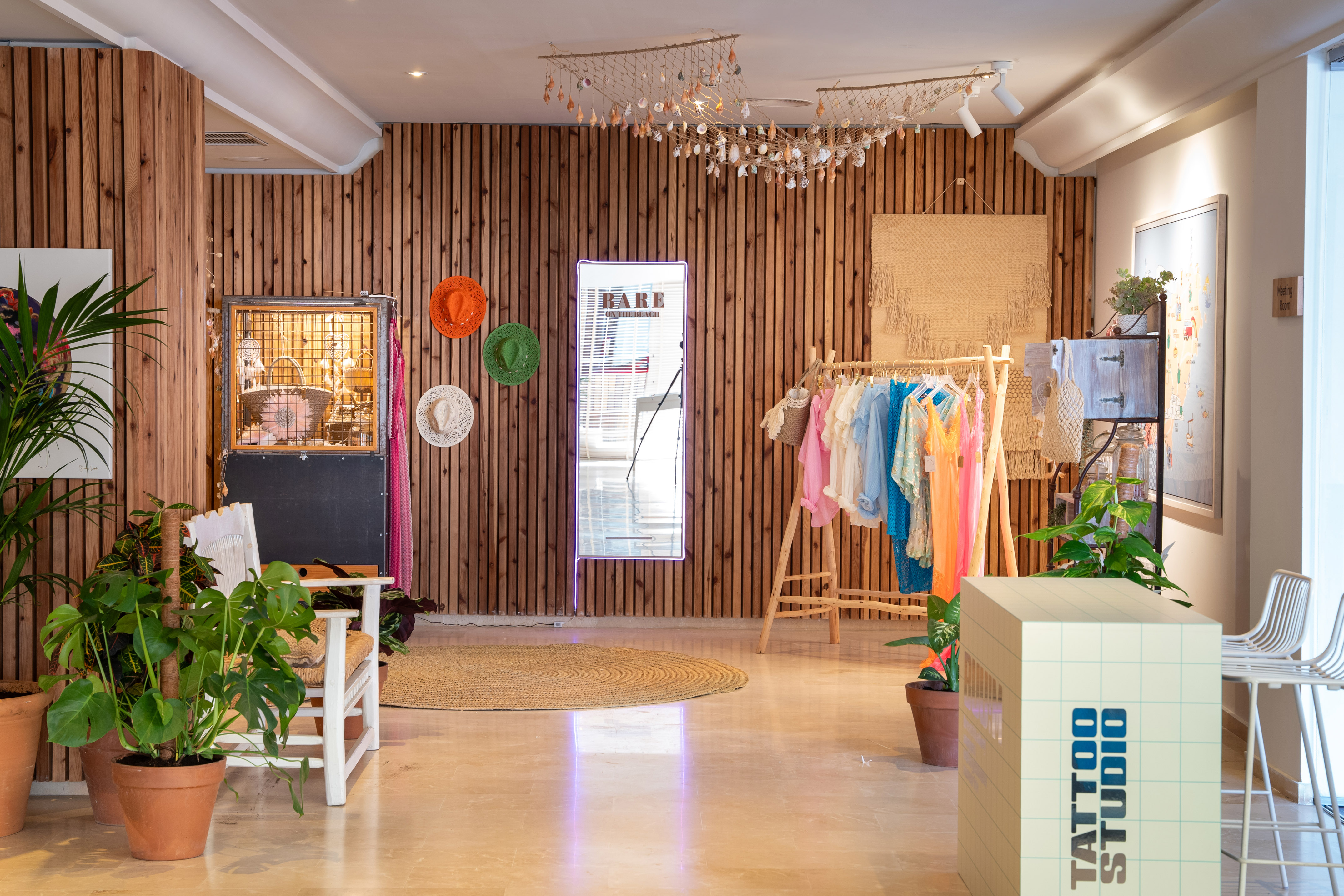 Vibrant clothing boutique with wooden walls, plants, and a Tattoo Studio.