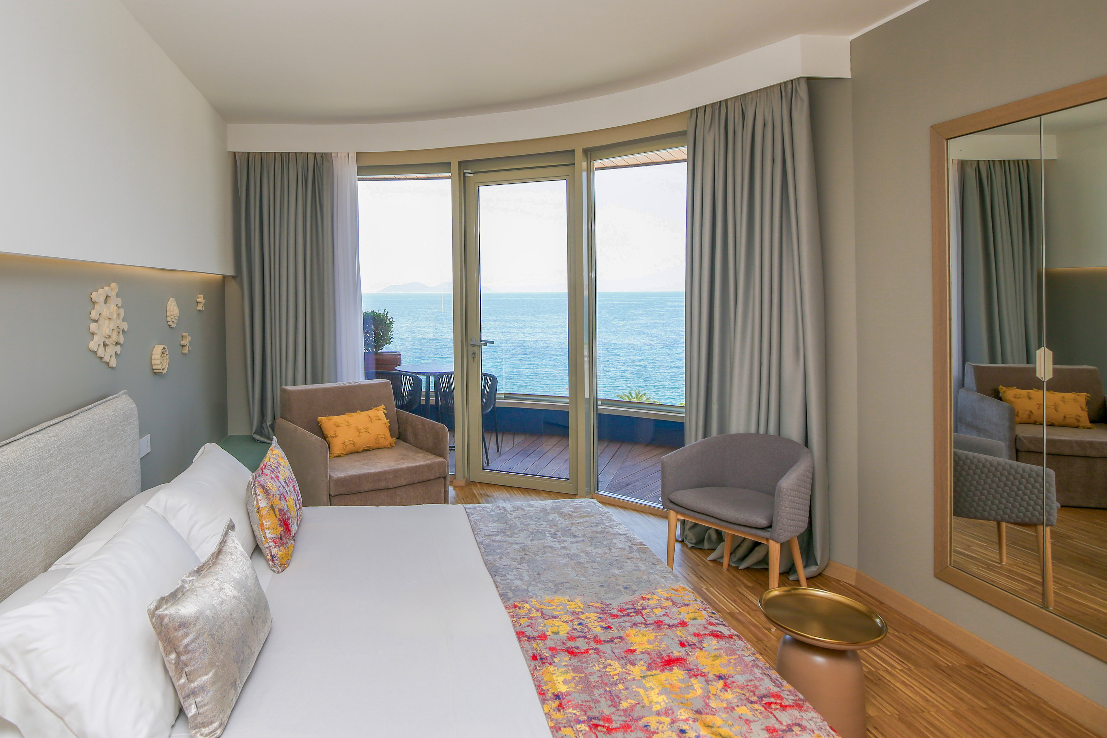 Modern hotel room with ocean view balcony, king bed, and stylish decor.