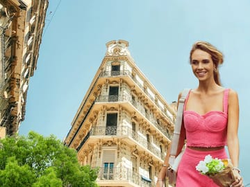 a woman in a pink dress walking in front of a building