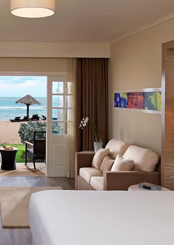a room with a bed and a couch and a beach view