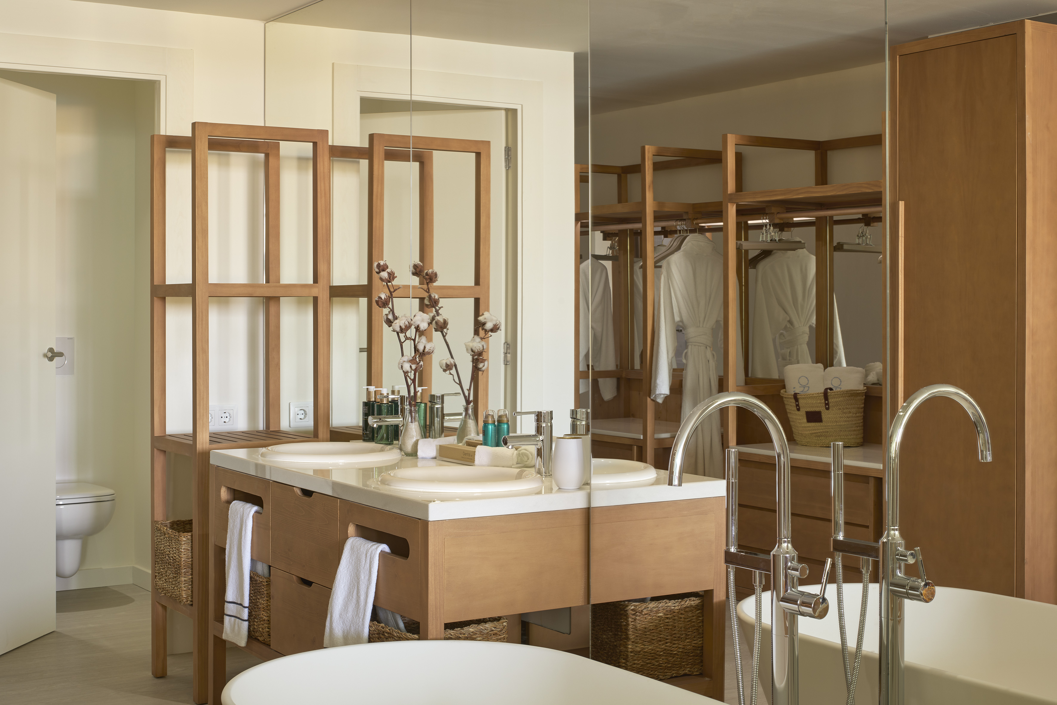Modern bathroom featuring wooden double vanity, white sinks, and bathtub.