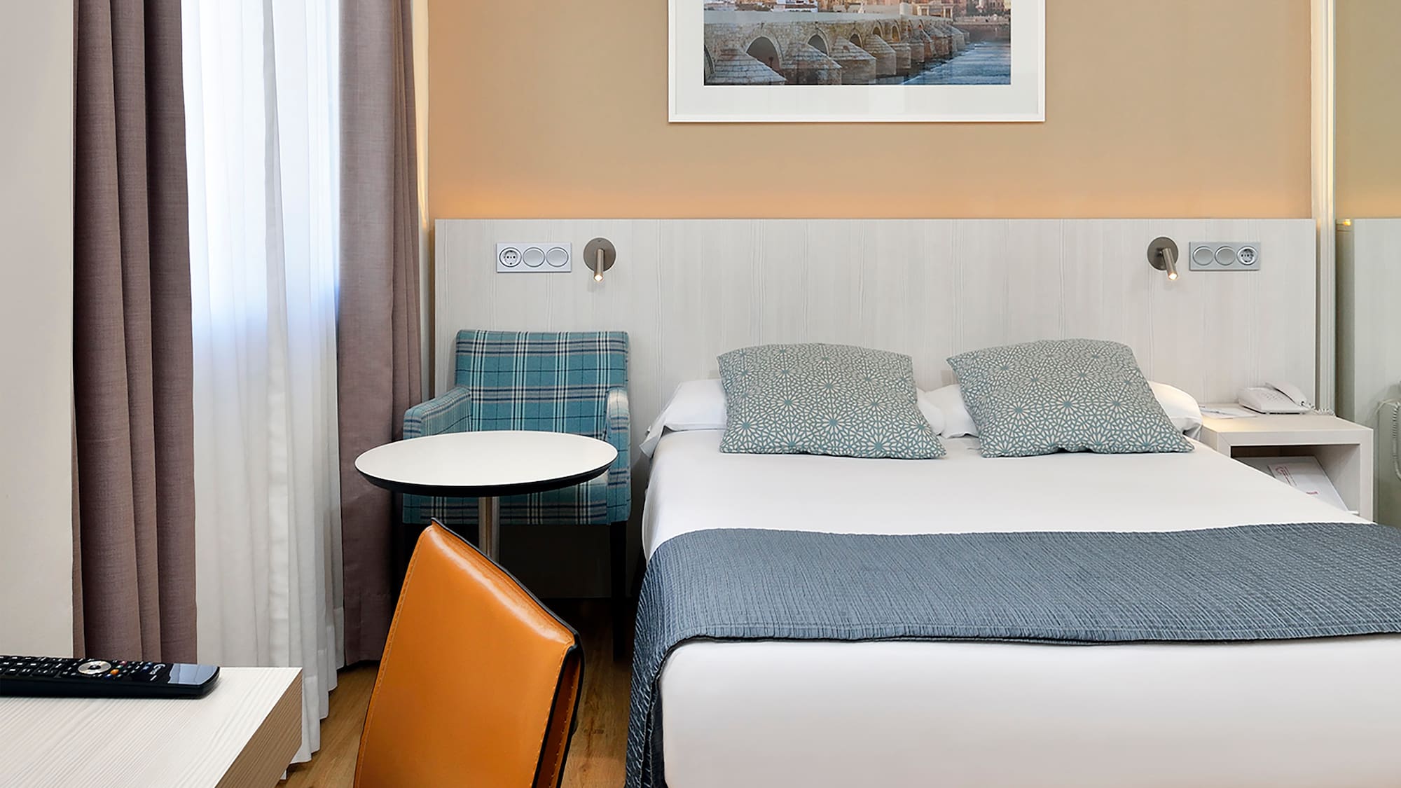 a bed with a chair and a table in a hotel room.