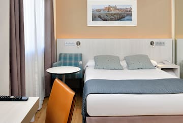 a bed with a chair and a table in a hotel room.