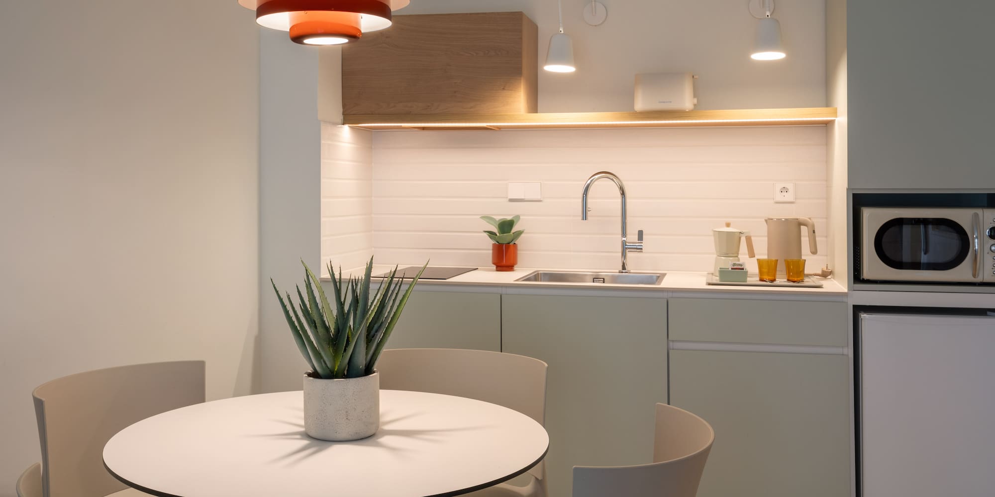 Modern kitchen and dining area with round table and red pendant light.