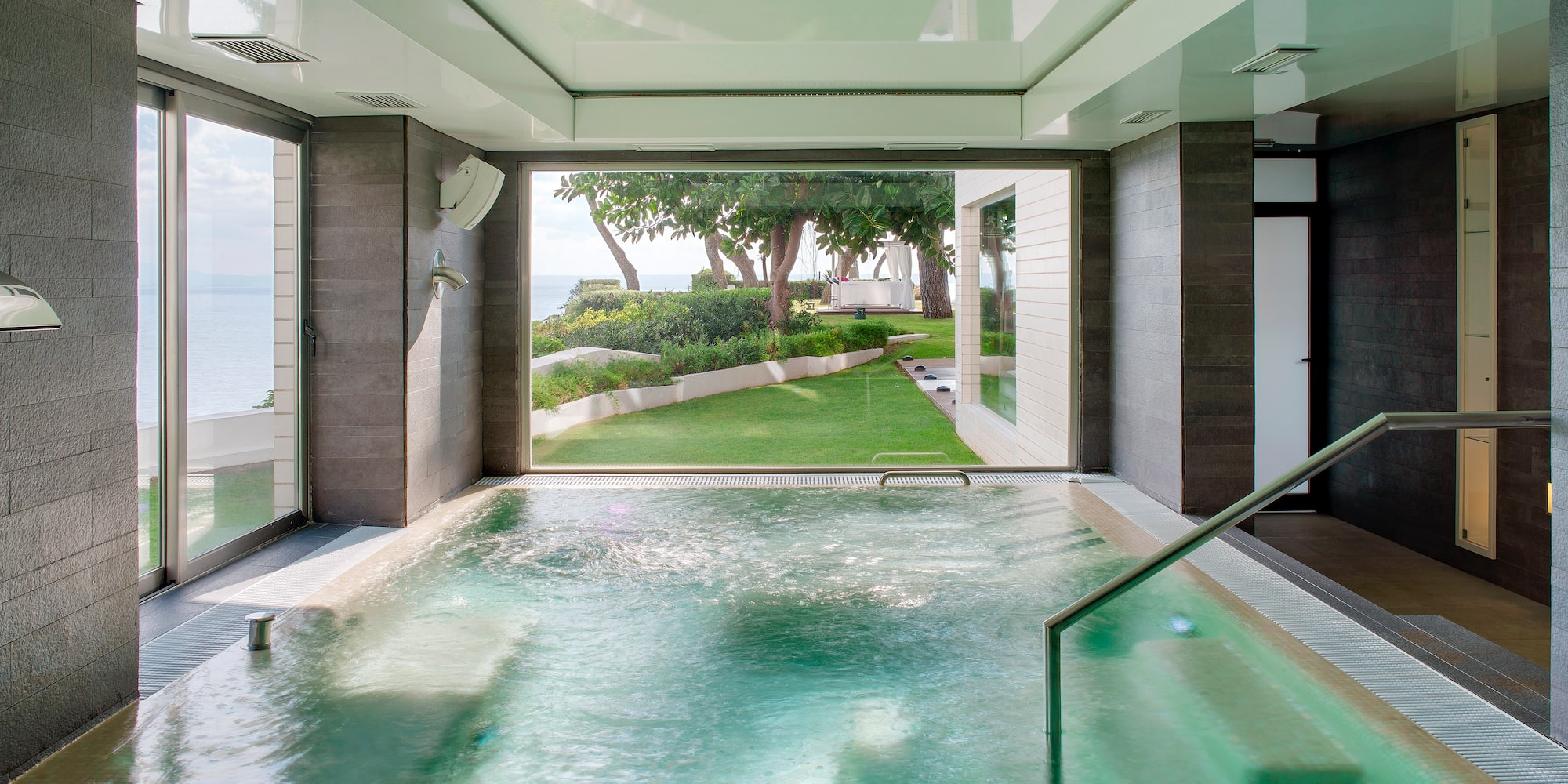 a pool with a staircase and a green lawn