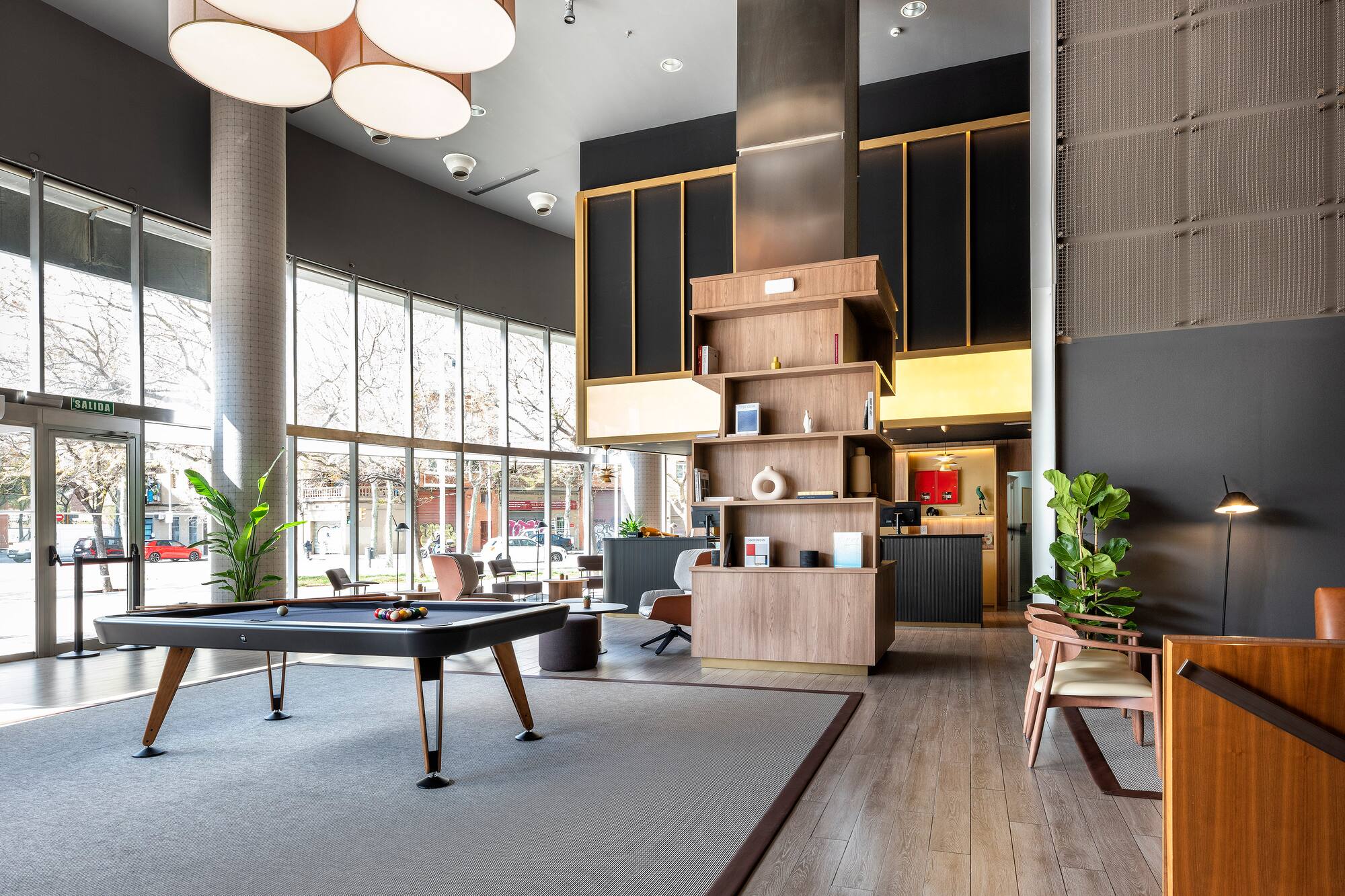 Modern hotel lounge with pool table, stylish decor, and large windows.