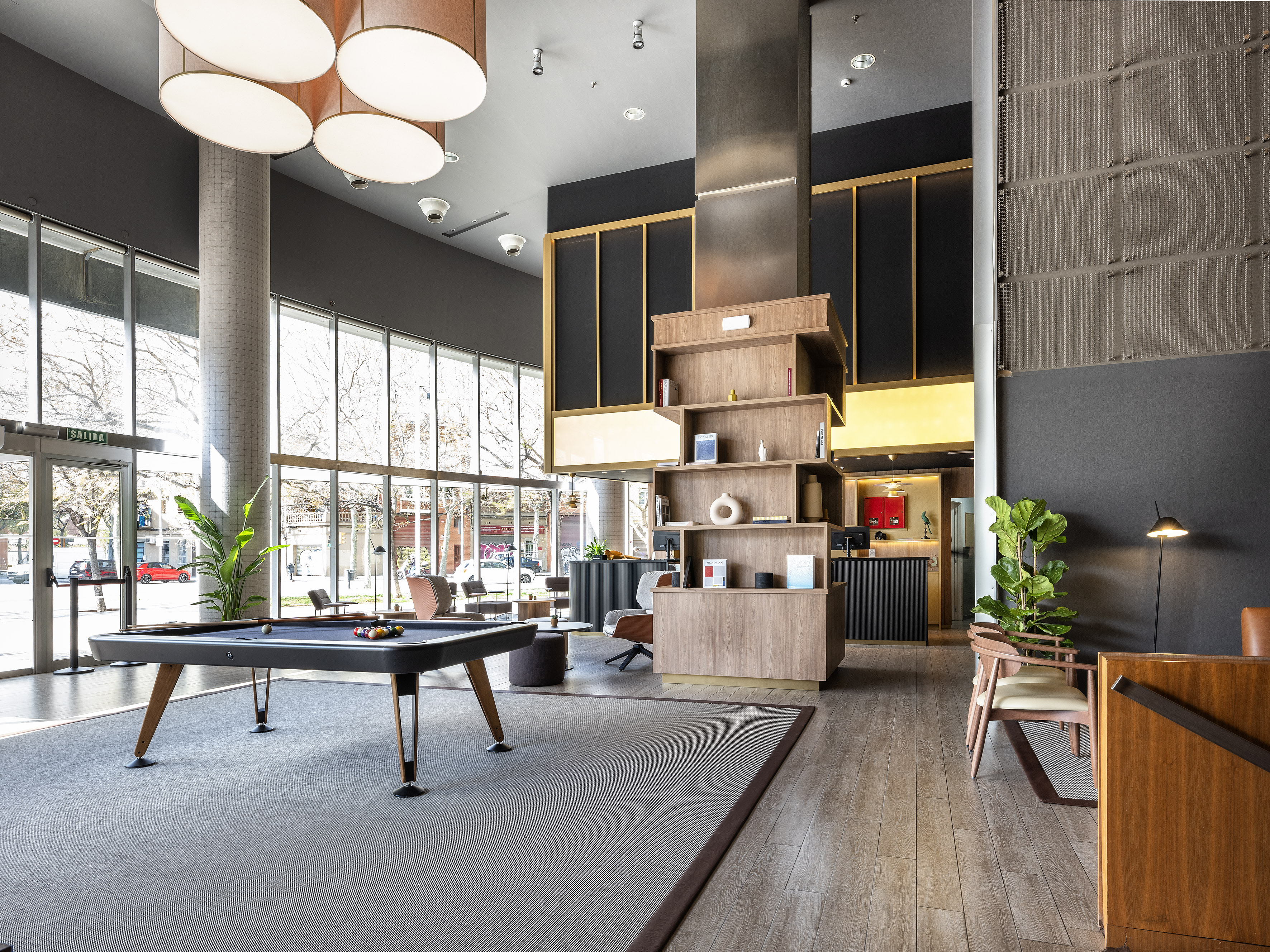 Modern hotel lounge with pool table, stylish decor, and large windows.