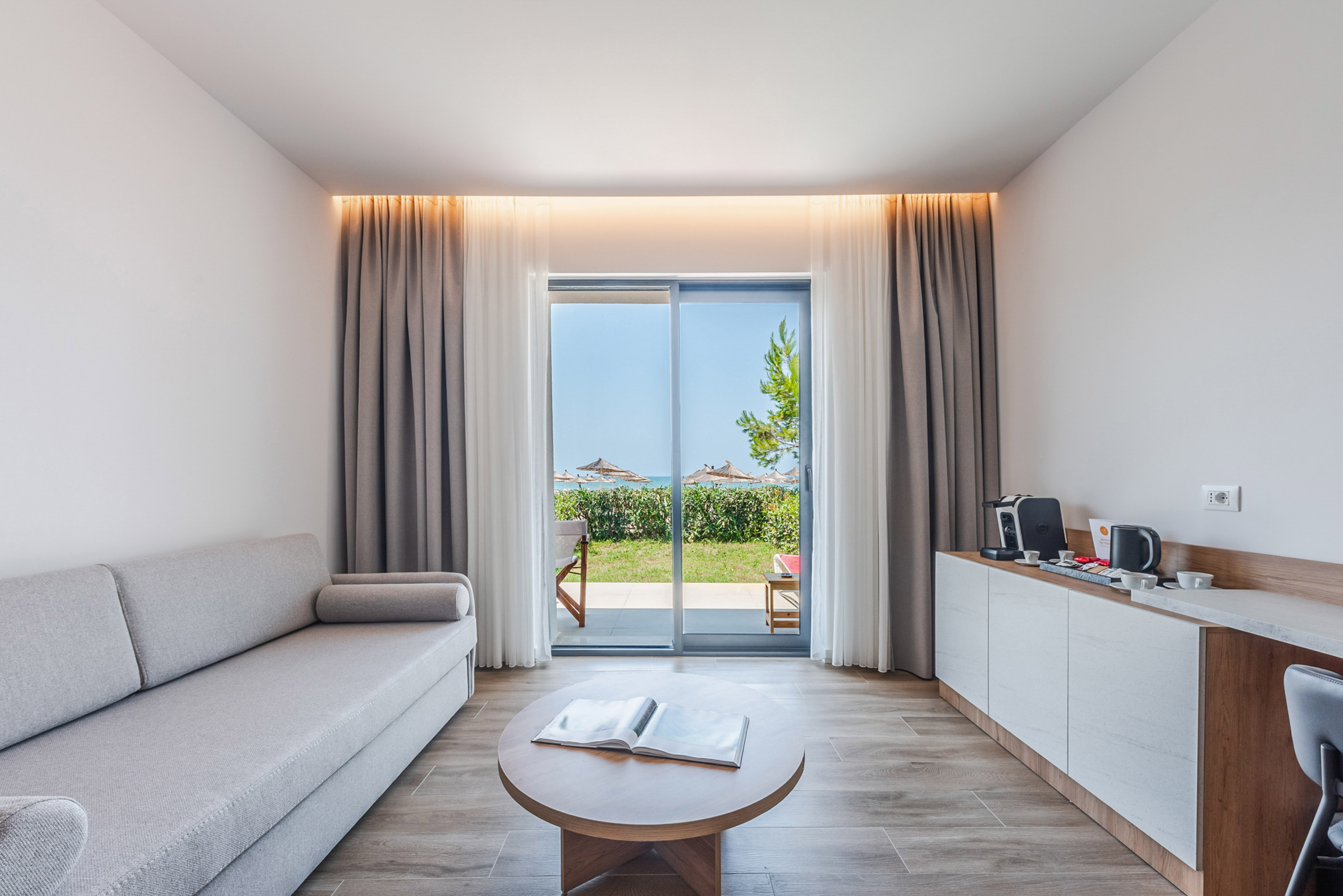 Contemporary hotel living room with sofa, coffee table, and beach view.