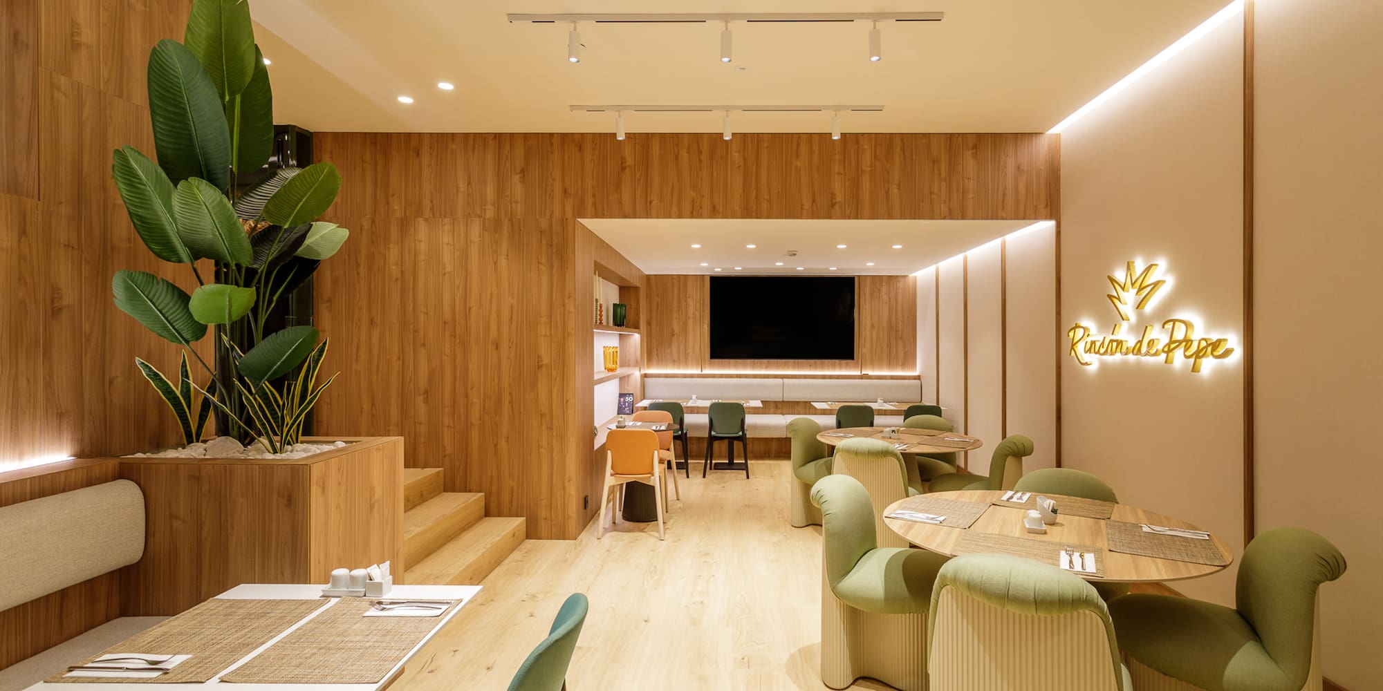 Modern restaurant with wood walls, green chairs, dining tables, and Rincón de Pepe sign.