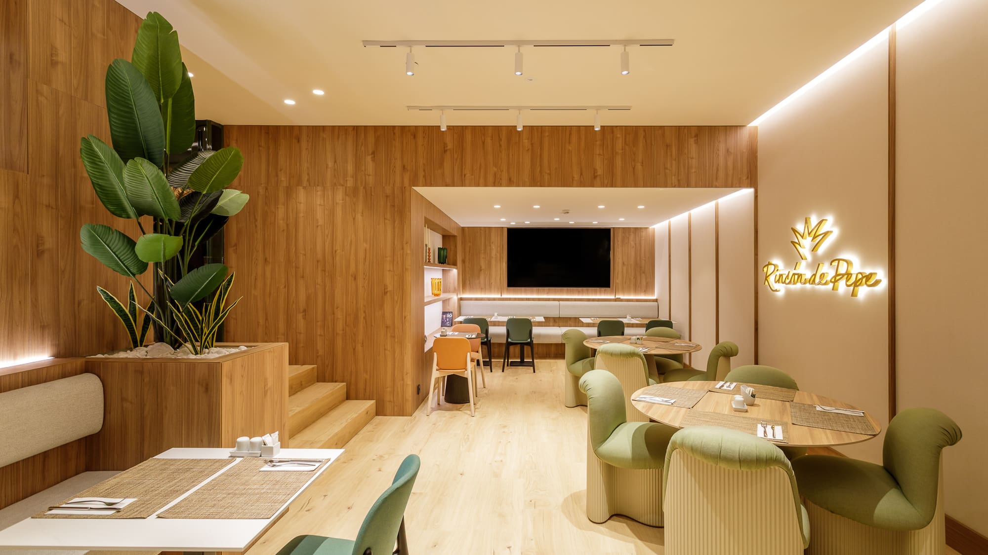 Modern restaurant with wood walls, green chairs, dining tables, and Rincón de Pepe sign.