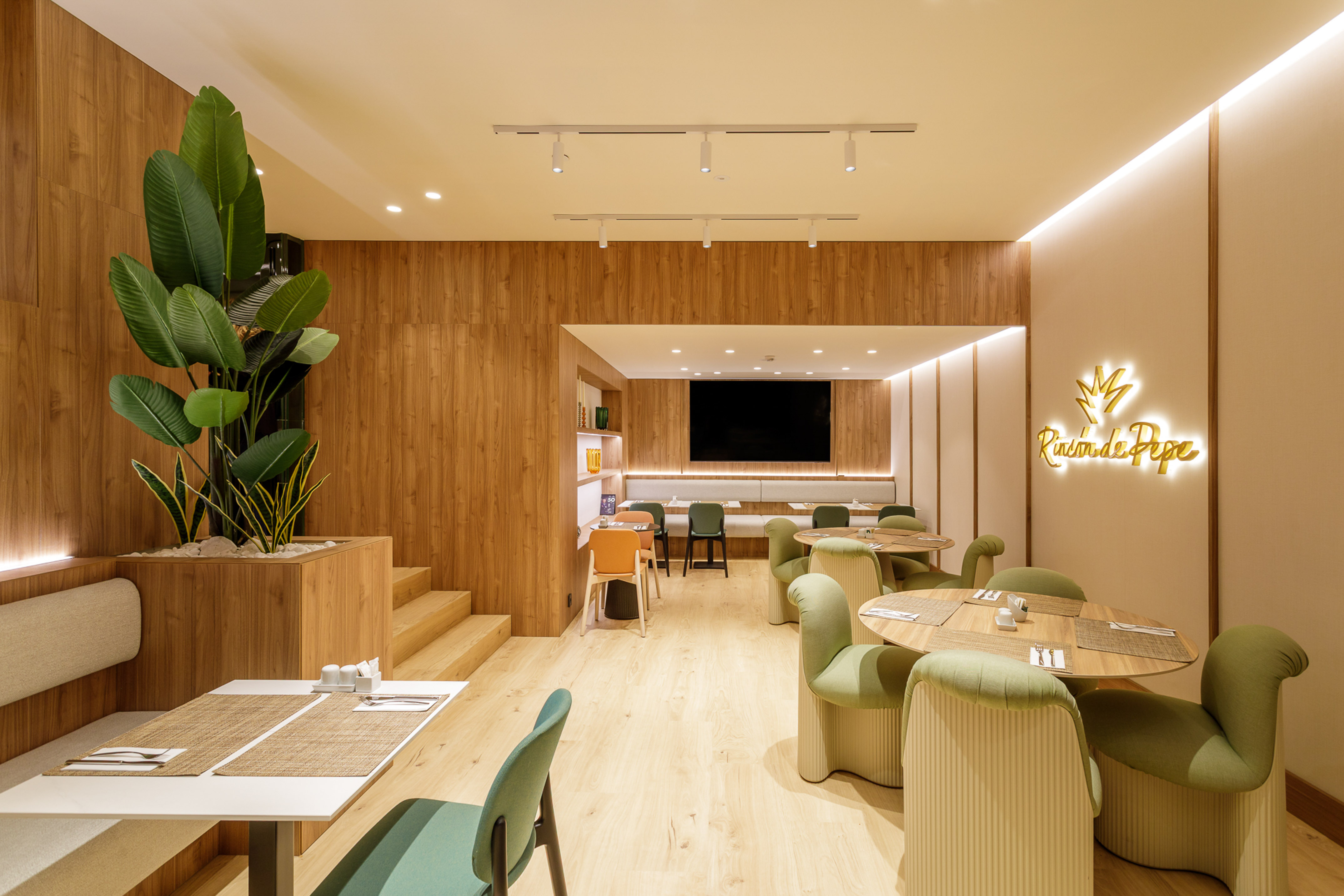 Modern restaurant with wood walls, green chairs, dining tables, and Rincón de Pepe sign.