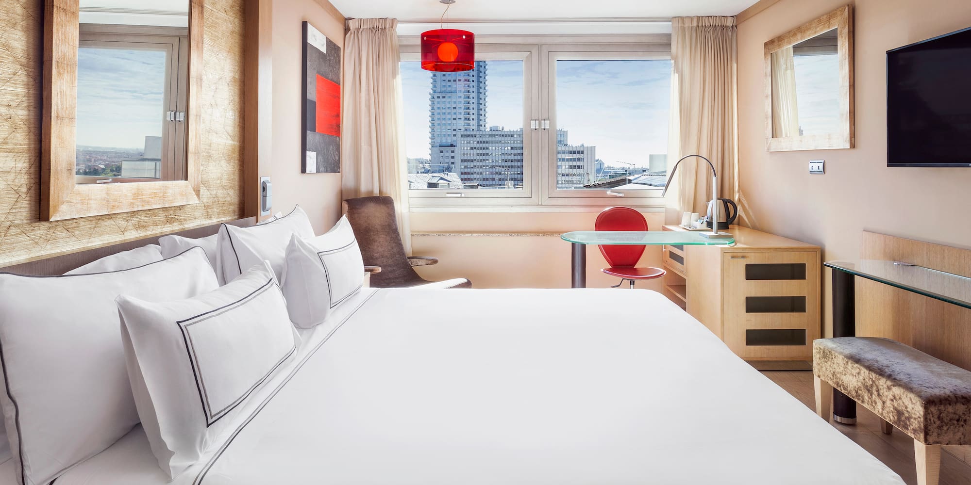 a bed with white sheets and a red lamp in a room with a window