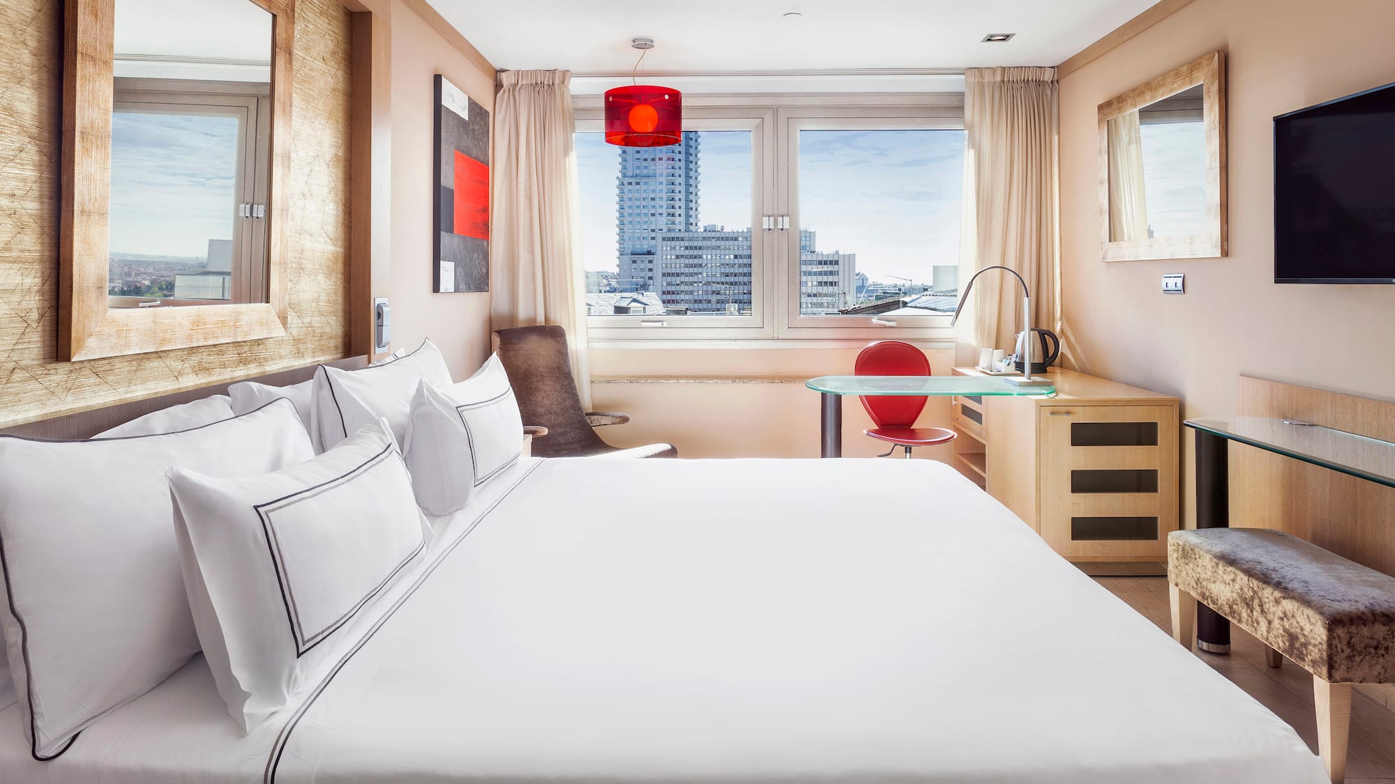 a bed with white sheets and a red lamp in a room with a window