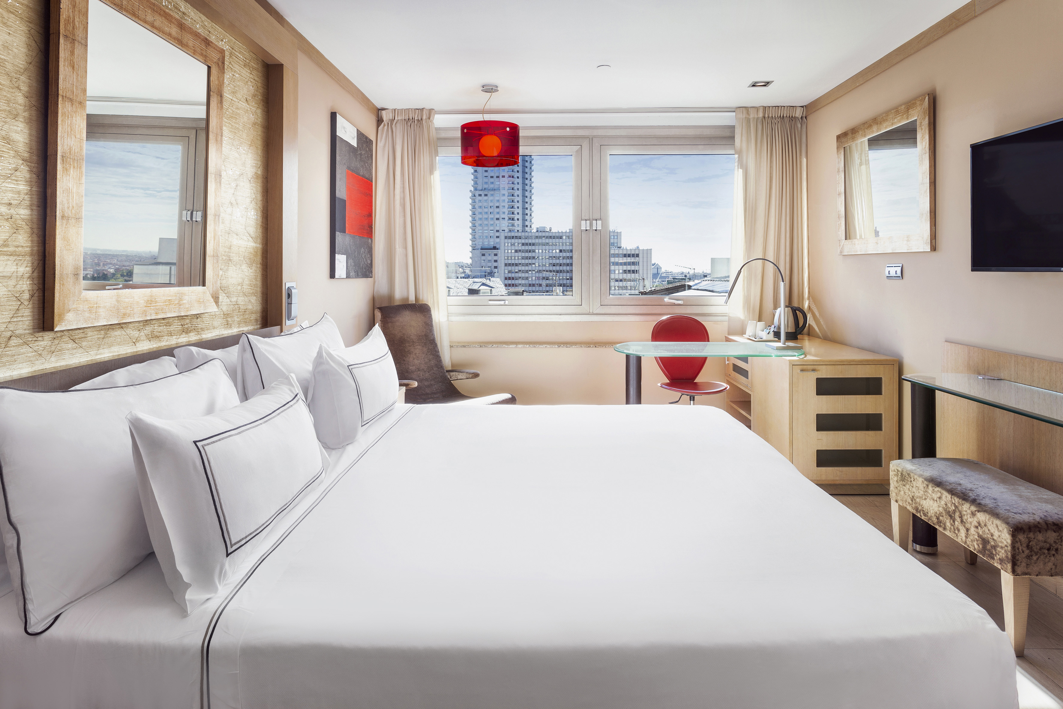 a bed with white sheets and a red lamp in a room with a window