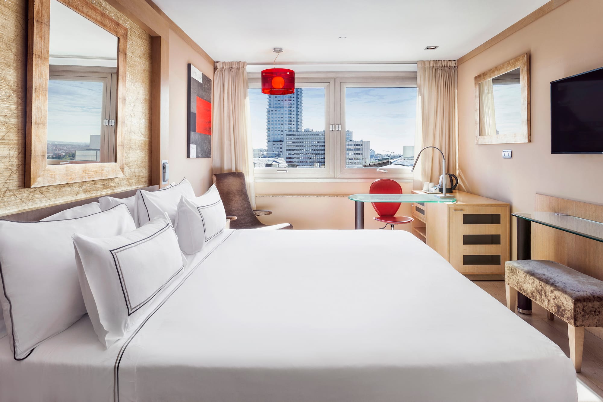 a bed with white sheets and a red lamp in a room with a window