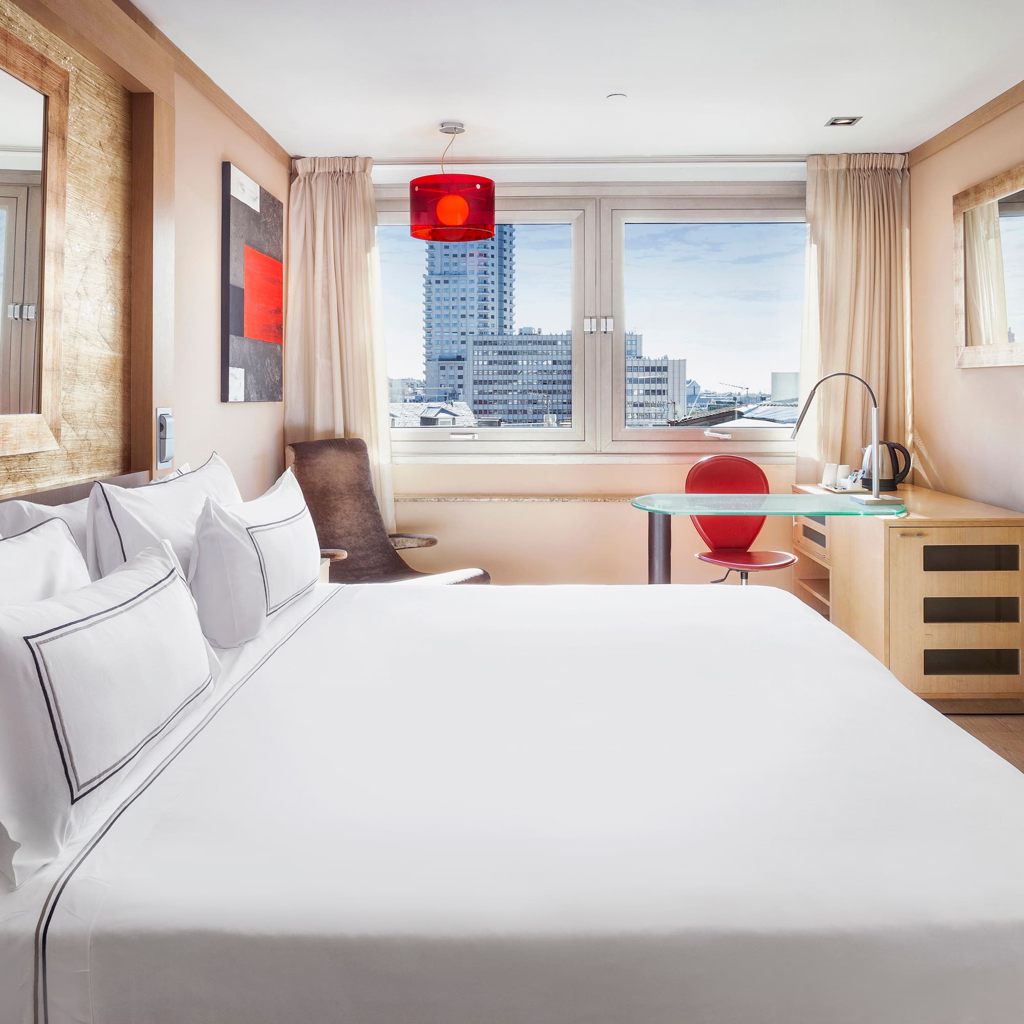 a bed with white sheets and a red lamp in a room with a window