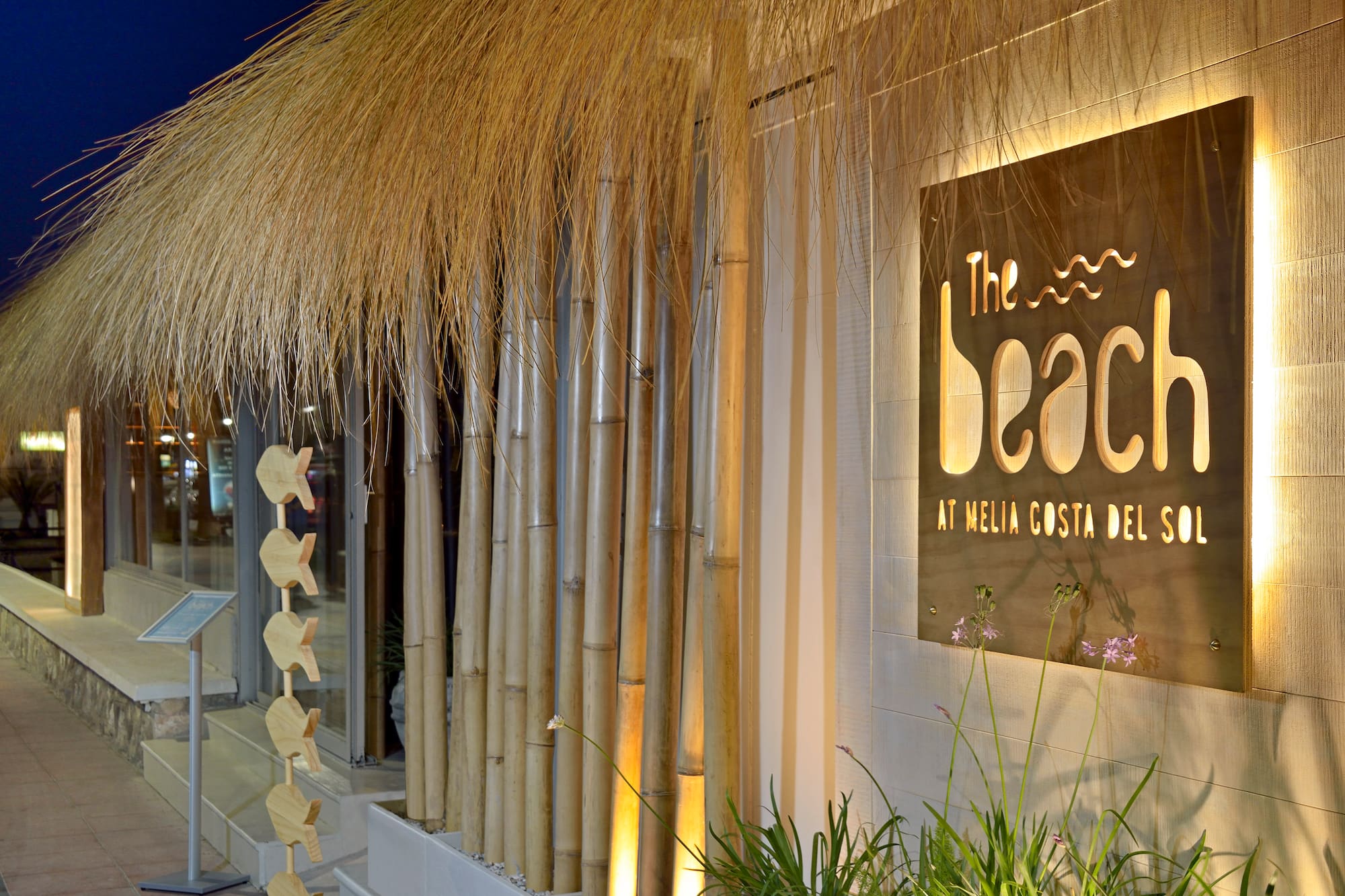 Illuminated 'The Beach' sign, Meliá Costa del Sol, thatched roof, bamboo.