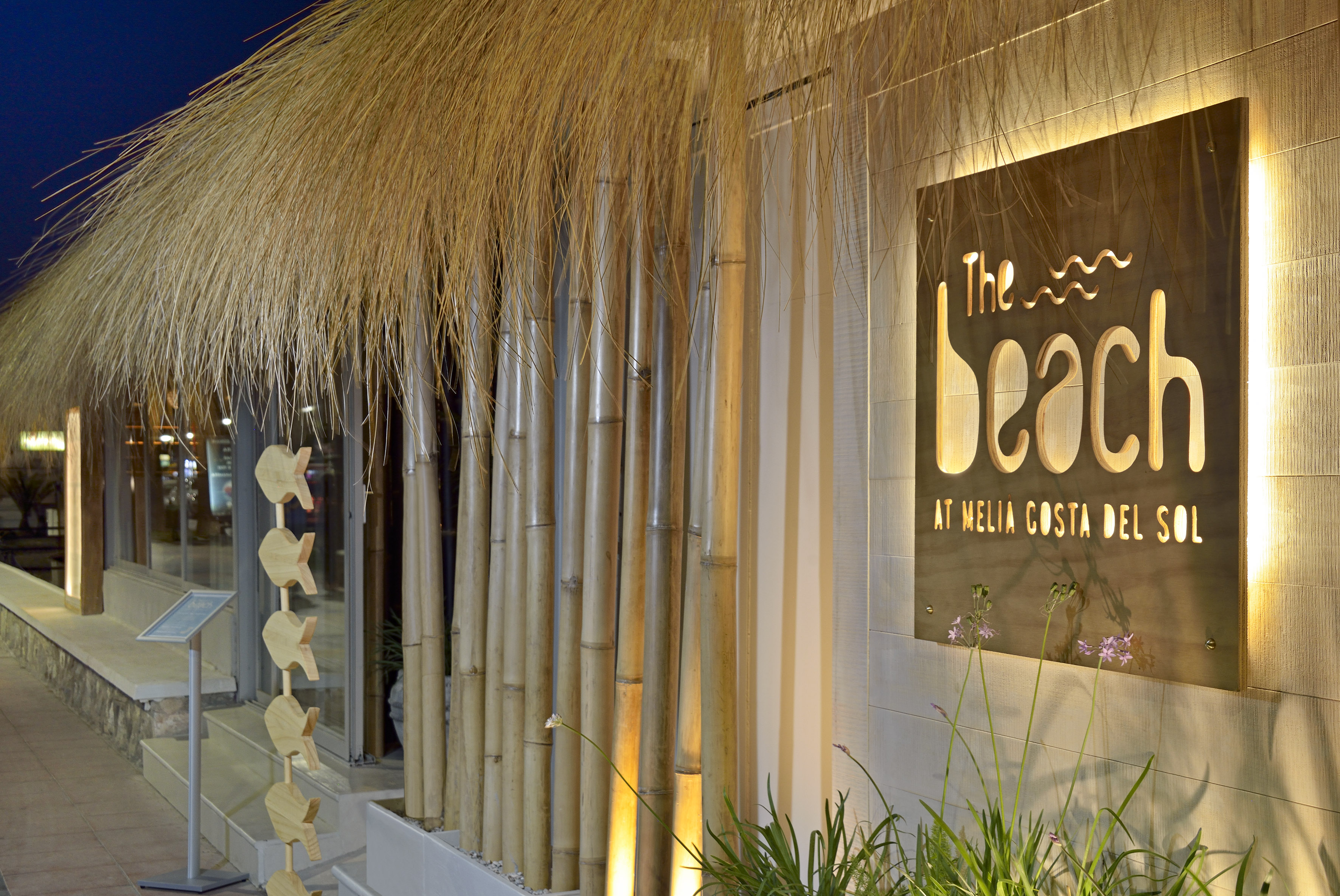 Illuminated 'The Beach' sign, Meliá Costa del Sol, thatched roof, bamboo.