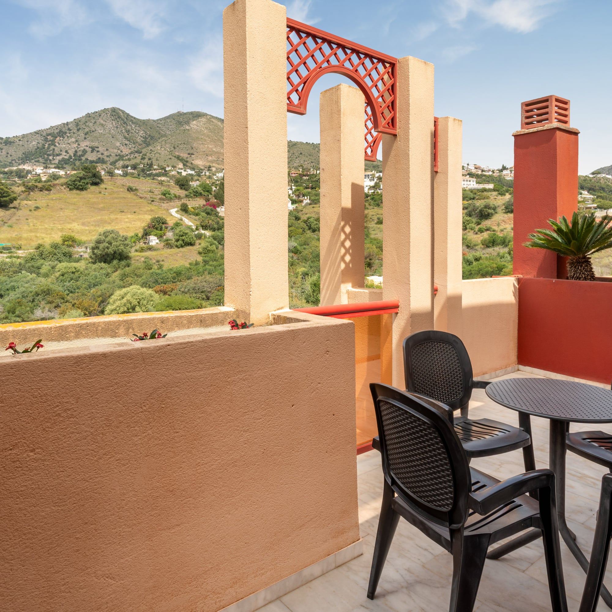 Mediterranean terrace with mountain view, outdoor seating, and red architectural details.