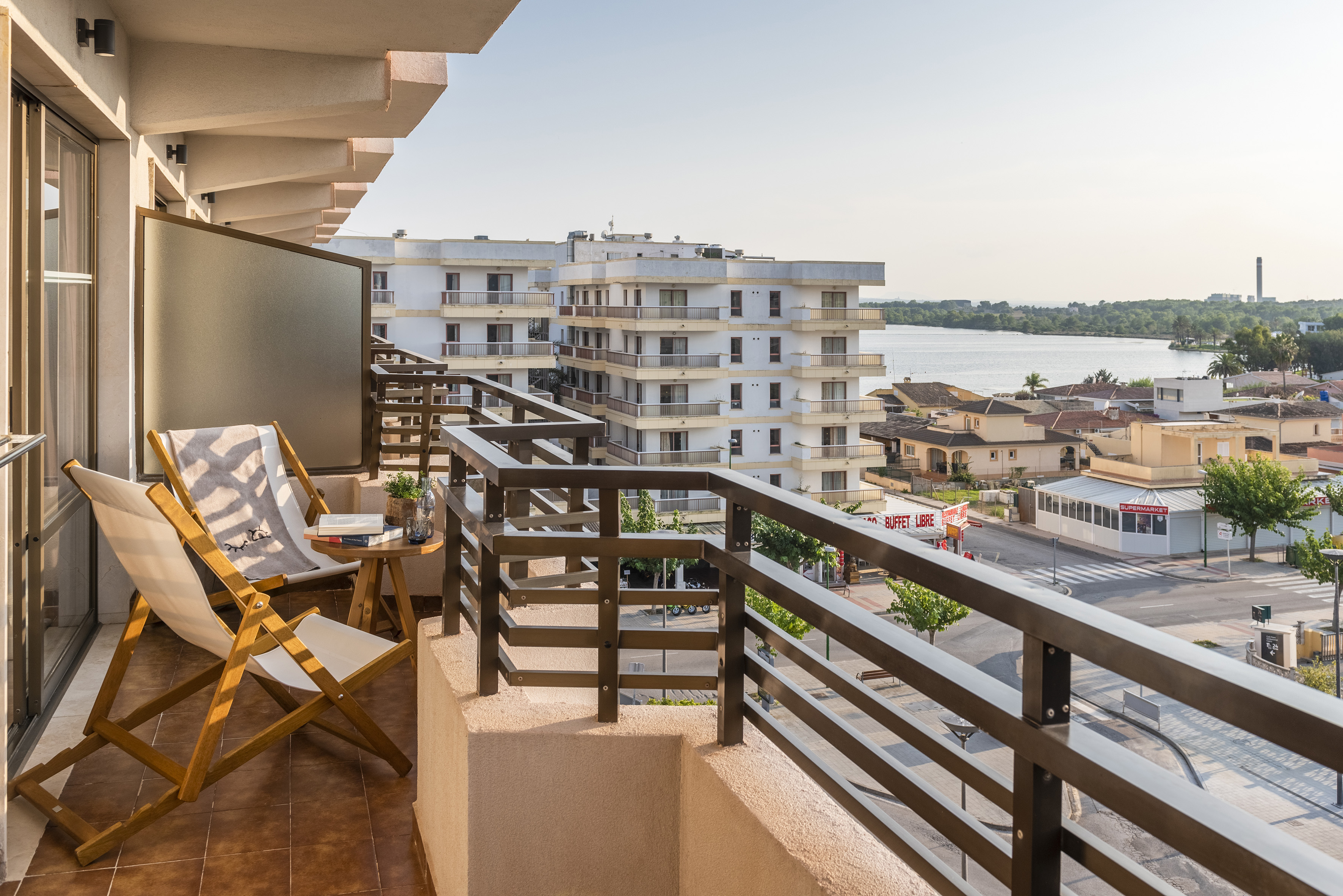 Sunny balcony with lounge chairs overlooking waterfront and town.