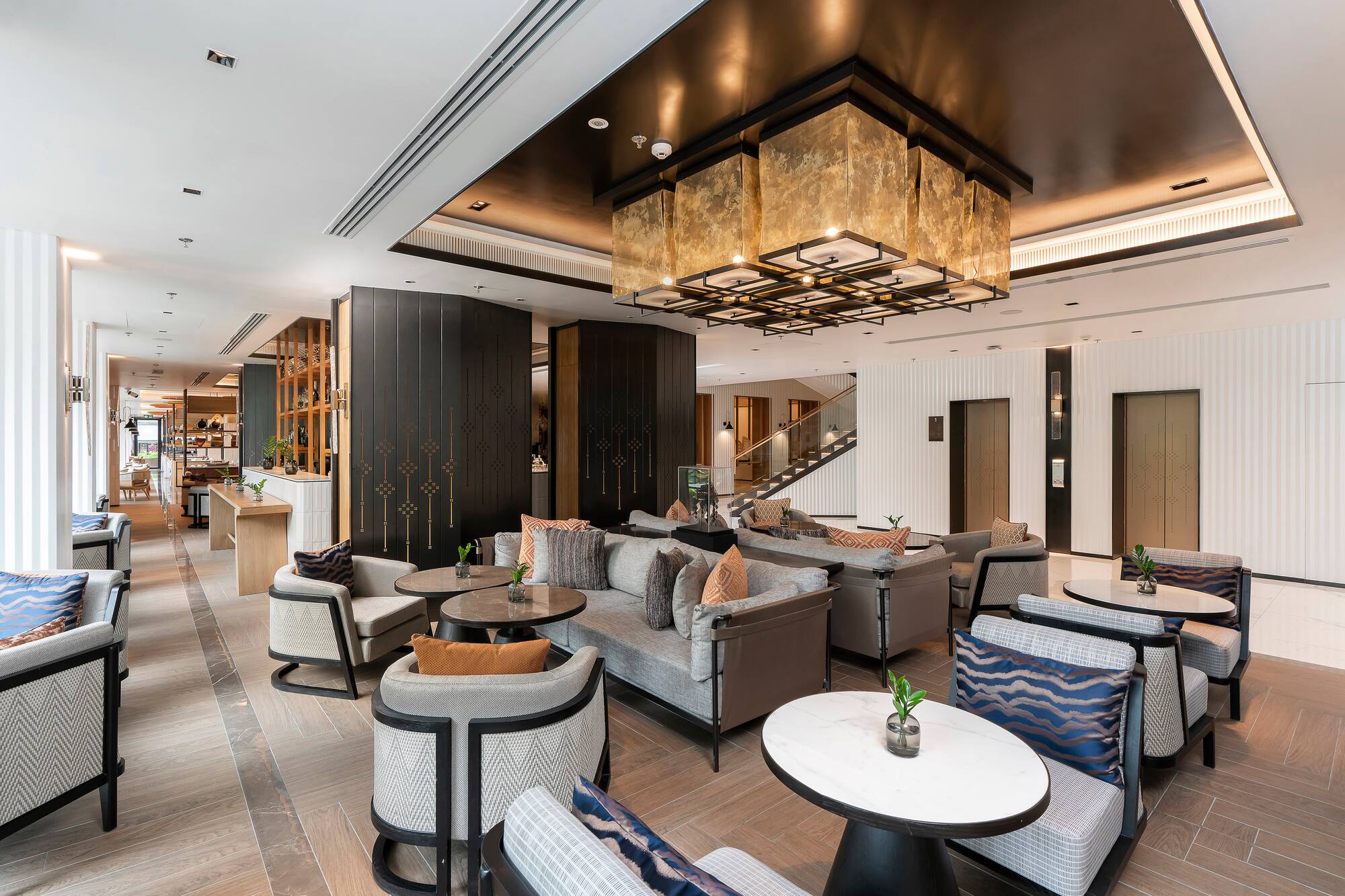Luxury hotel lobby lounge with modern seating and grand gold chandelier.