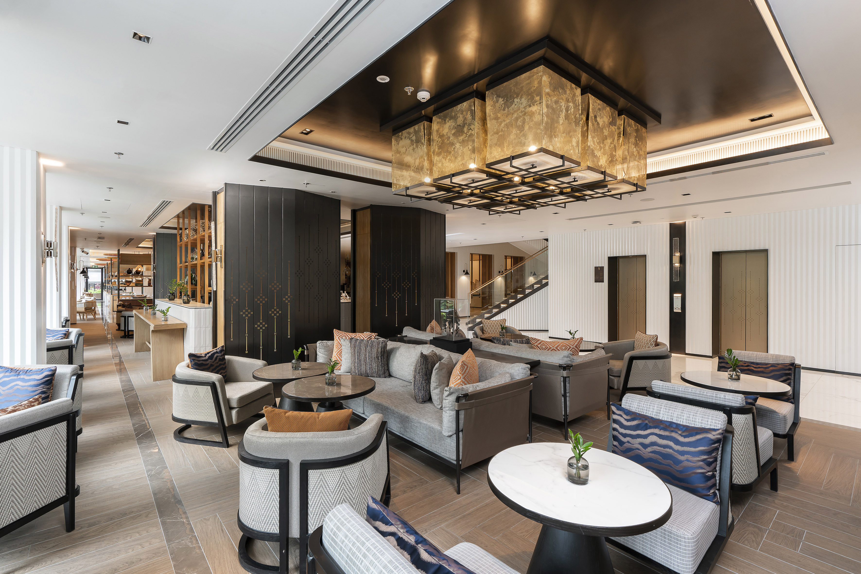 Luxury hotel lobby lounge with modern seating and grand gold chandelier.